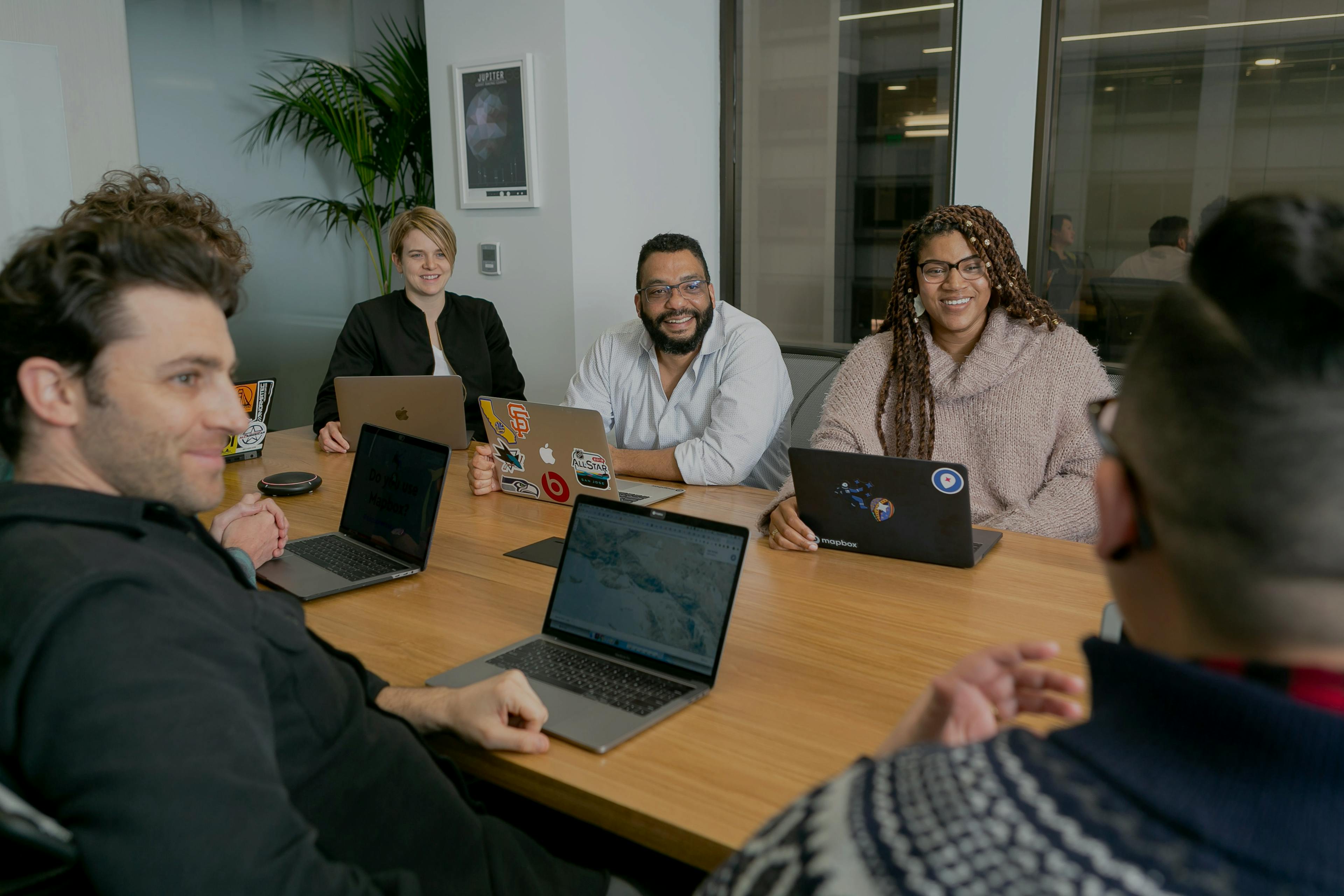 Four people in meeting room on laptops