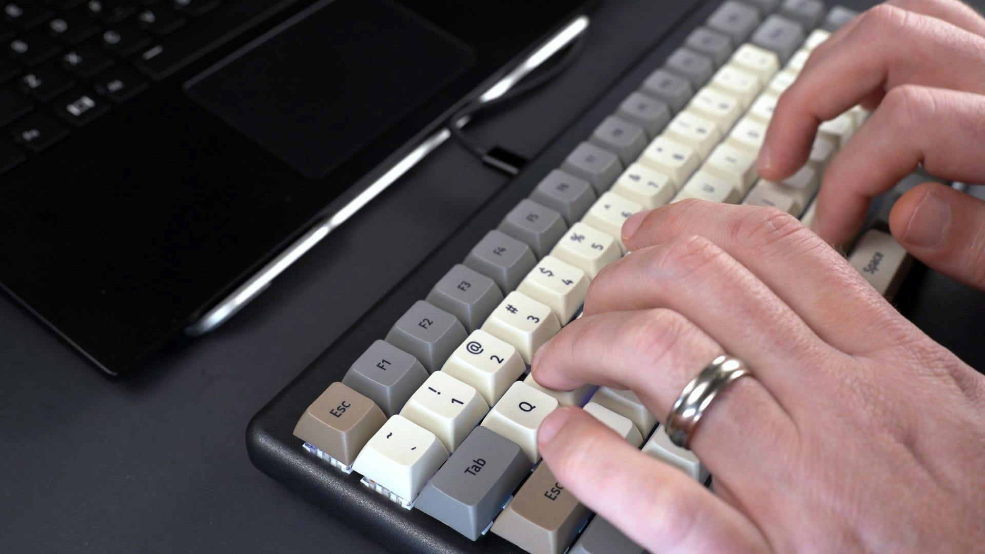 A person typing on the keyboard that is plugged into the laptop.