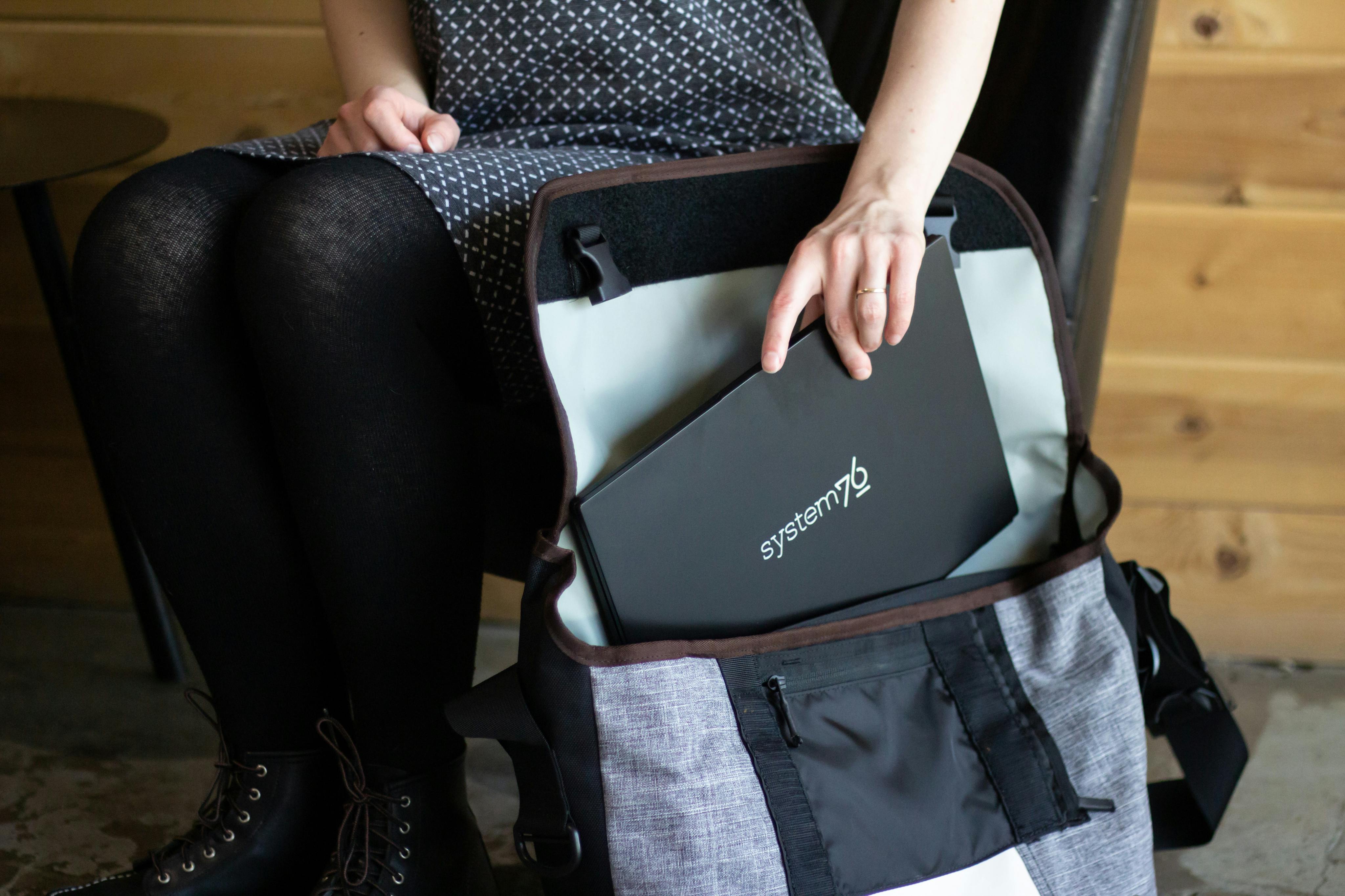 A person storing their Lemur Pro laptop in their System76 messenger bag.