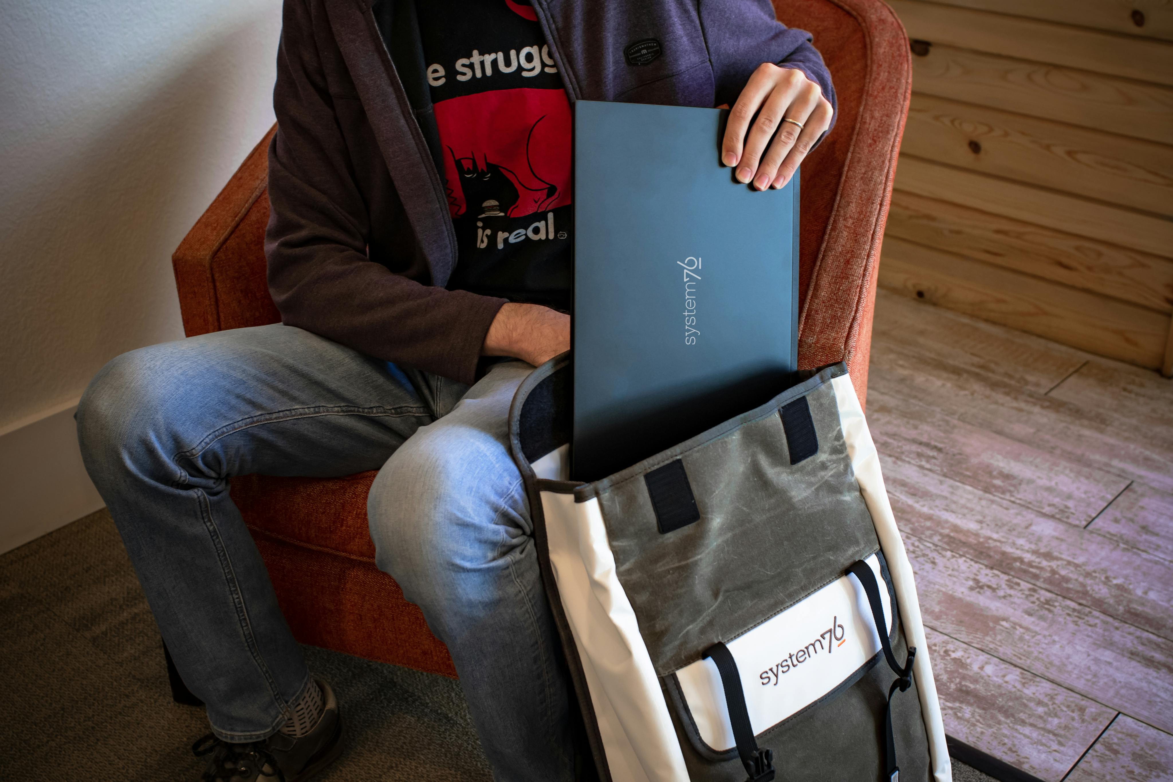 A person storing their Pangolin laptop in the System76 messenger bag.