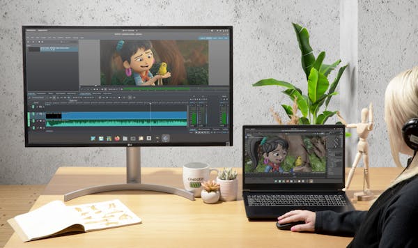 An animator uses an Adder laptop to edit an animation connected to a monitor. 