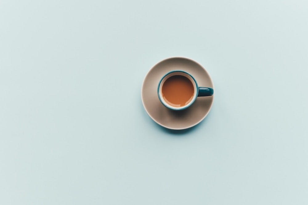 small cup of espresso on blue background.