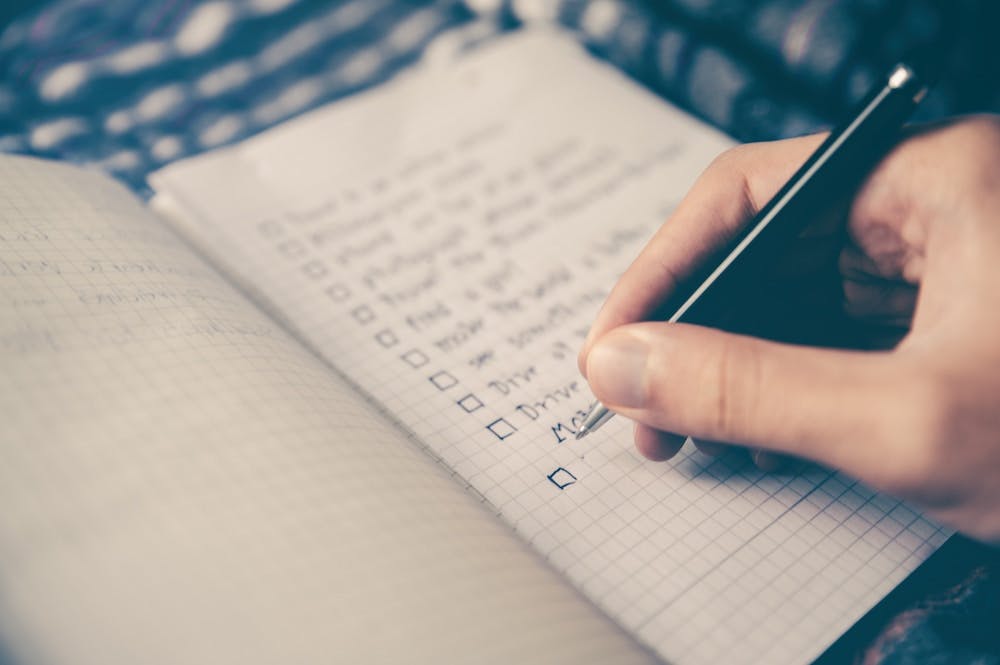 Man writing down a checklist in a notepad.