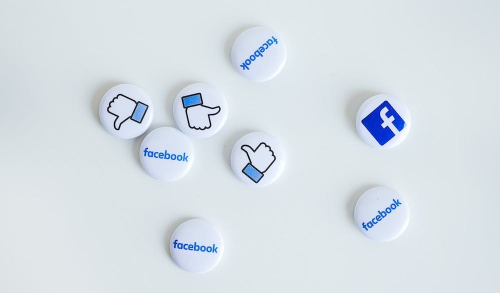 Enamel pins with Facebook logo and thumbs up.
