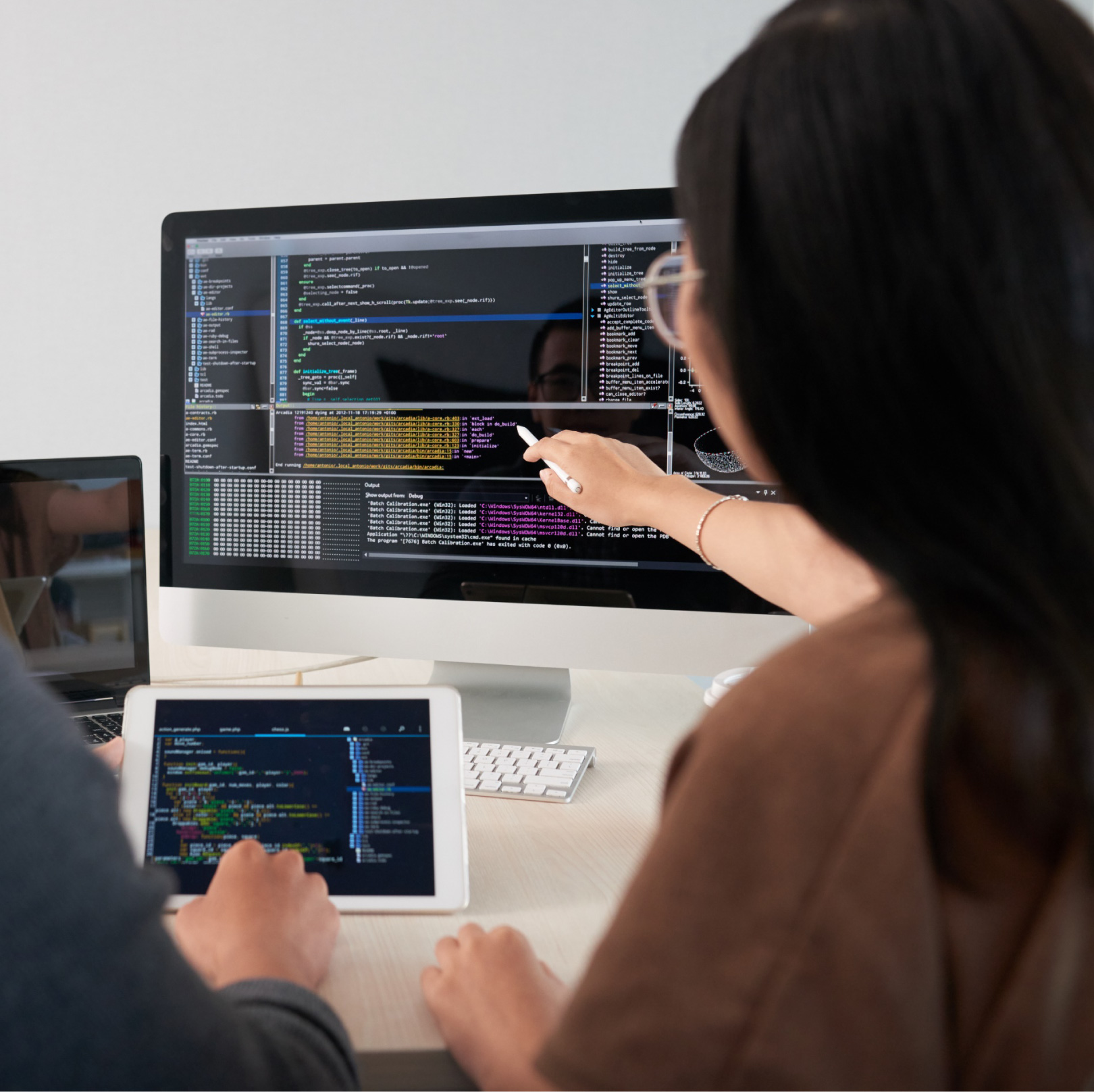 Two individuals looking at a screen with one person pointing at it