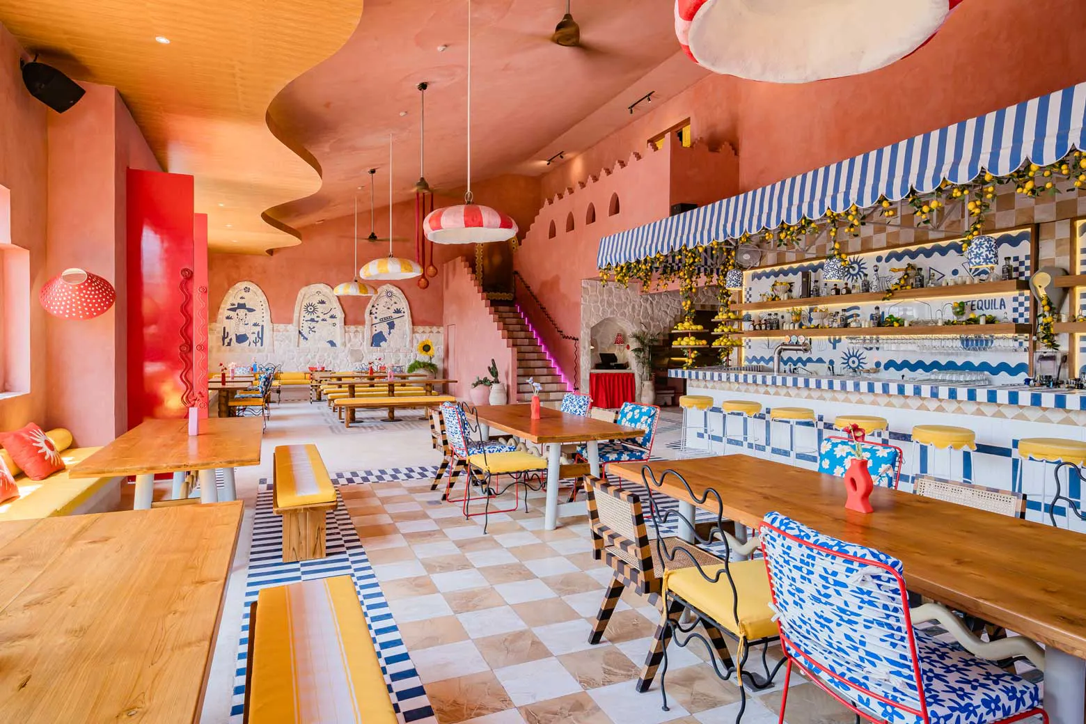 Wide view of vibrant Mexican restaurant in Uluwatu Bali featuring wavy ceiling, tequila bar and eclectic mismatched chairs