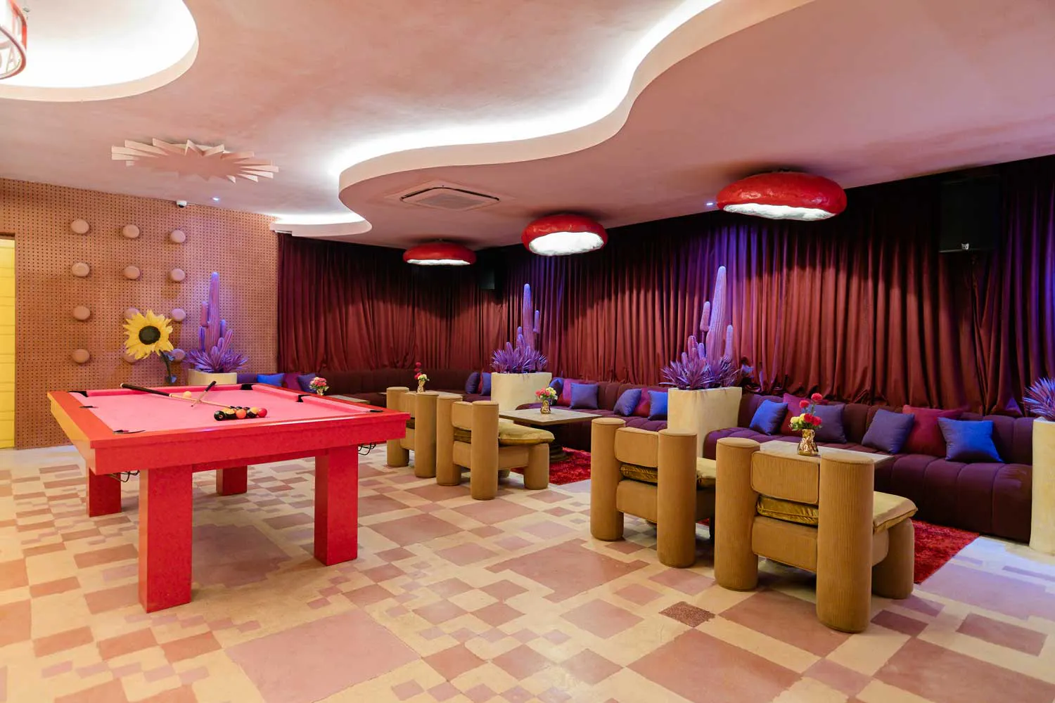 Private function room in Uluwatu Bali featuring red pool table, dark velvet banquette seating and glowing cactus installations