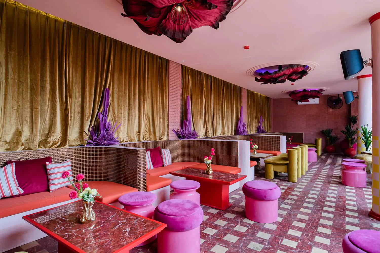 Club Corazon Bali lounge area with pink velvet banquettes, purple cactus decor, and gold curtains
