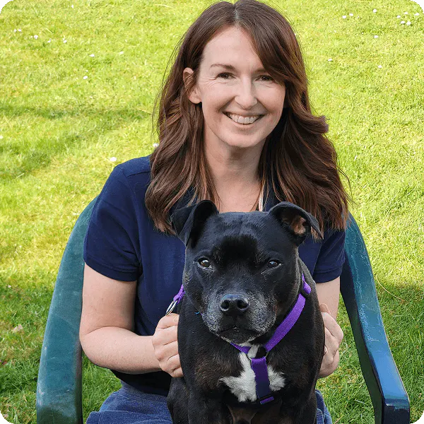 Nutritionist outside on grass with a black dog