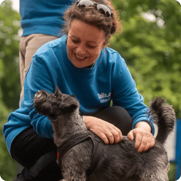 Behaviourist kneeling outside with a dog