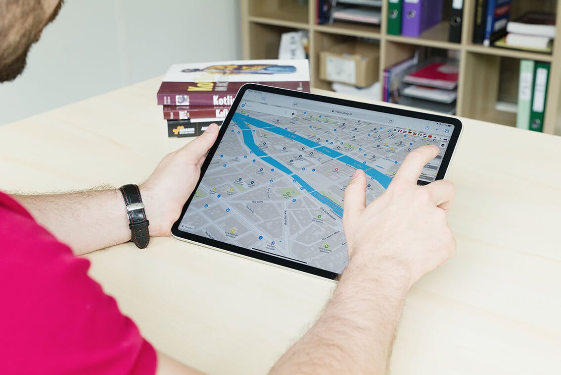 Groupe de quatre collègues souriants regardant une tablette autour d’une table