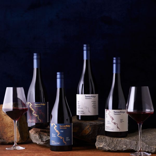 An image with 4 bottles of wine and 2 glasses with wine.