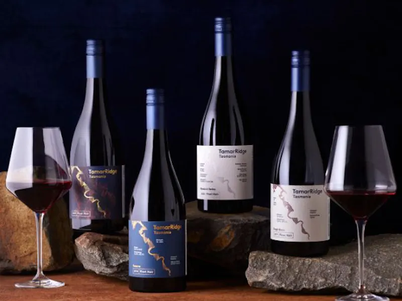 An image with 4 bottles of wine and 2 glasses with wine.