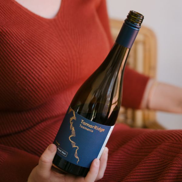 A woman holding an open bottle of wine
