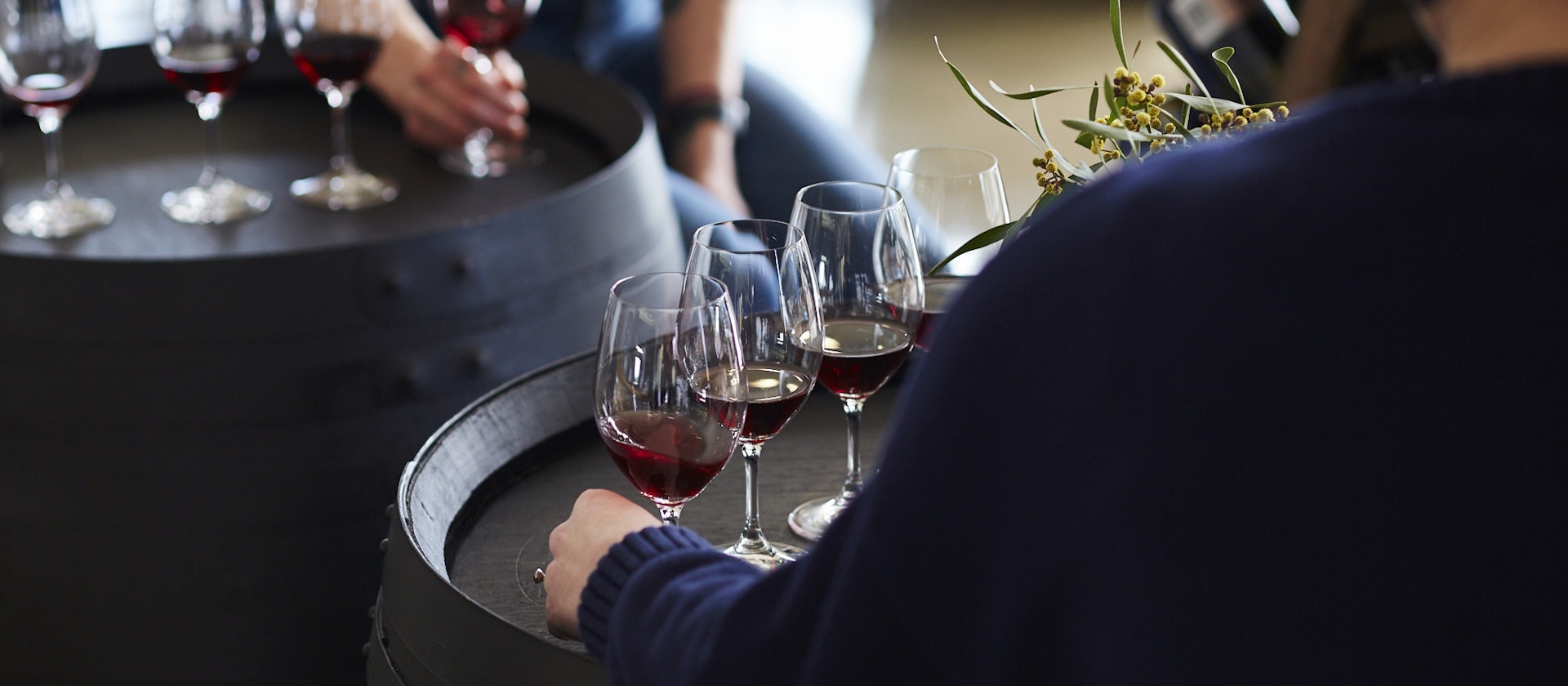 Person reaching for a glass of wine from a barrel