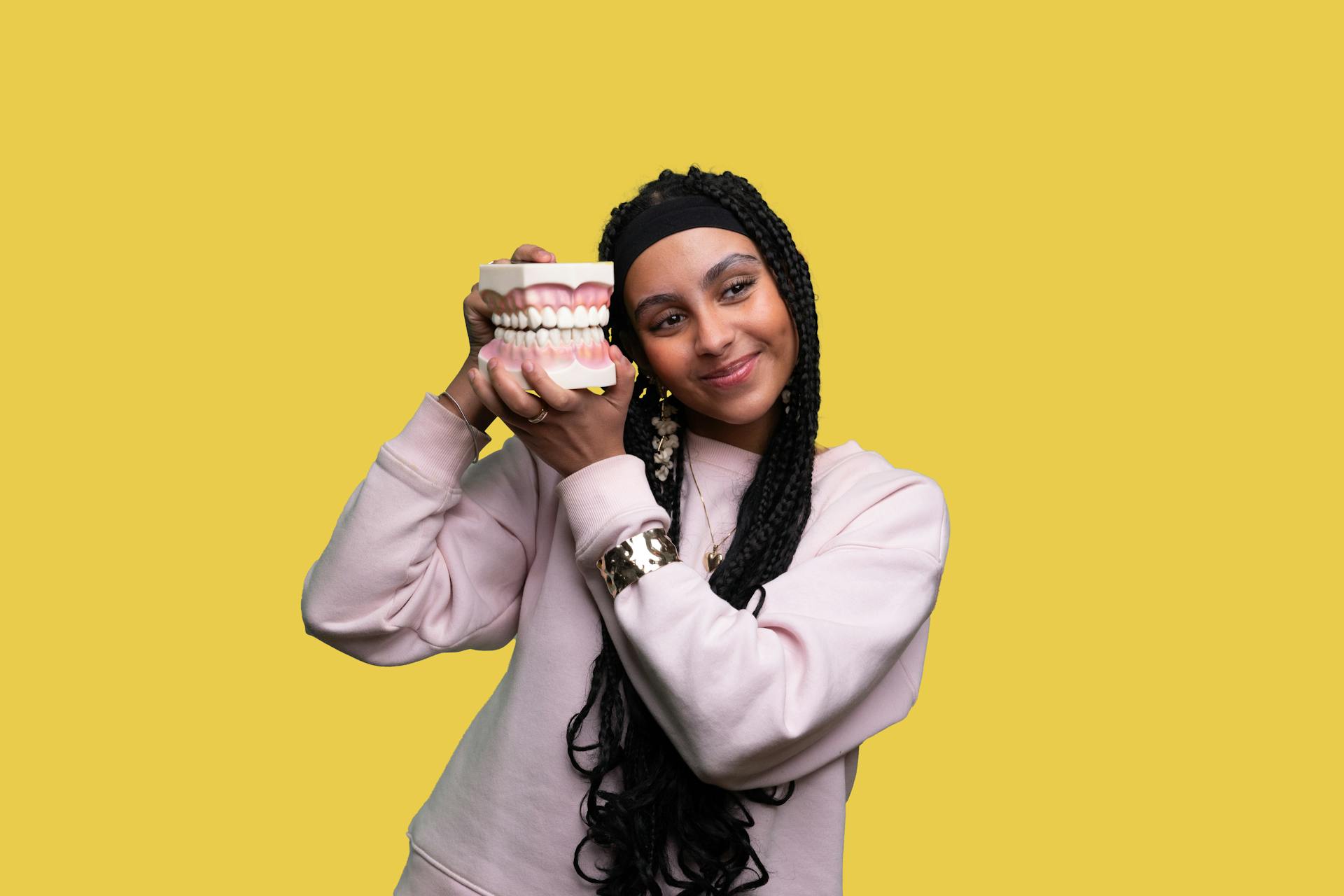 Girl holding model of teeth and smiling