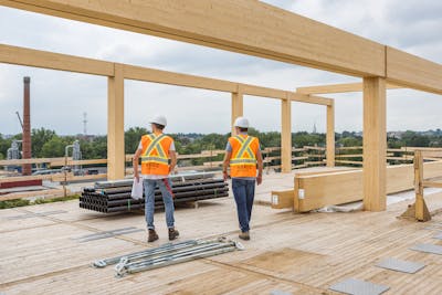 2 ouvriers sur un chantier de construction inspectent les structures en bois massif.