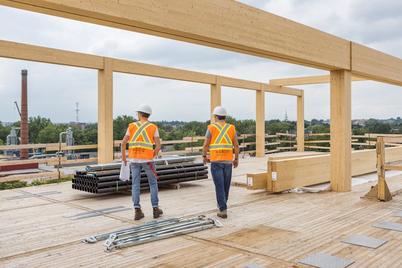 2 ouvriers sur un chantier de construction inspectent les structures en bois massif.
