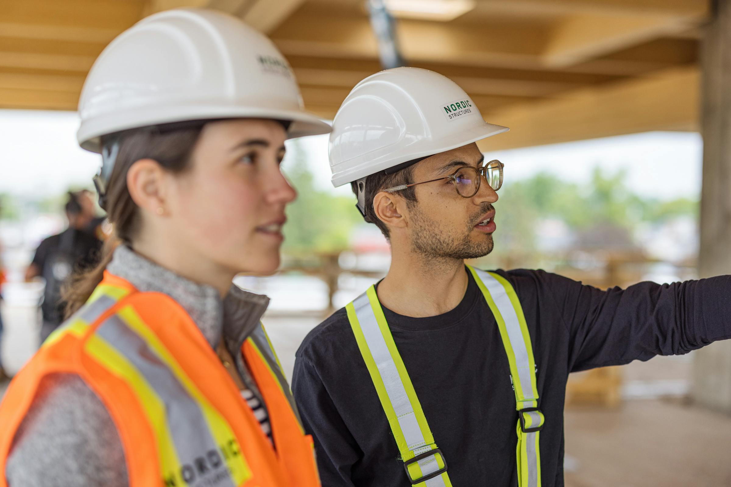 2 engineers discussing and pointing at a solid wood structural element.