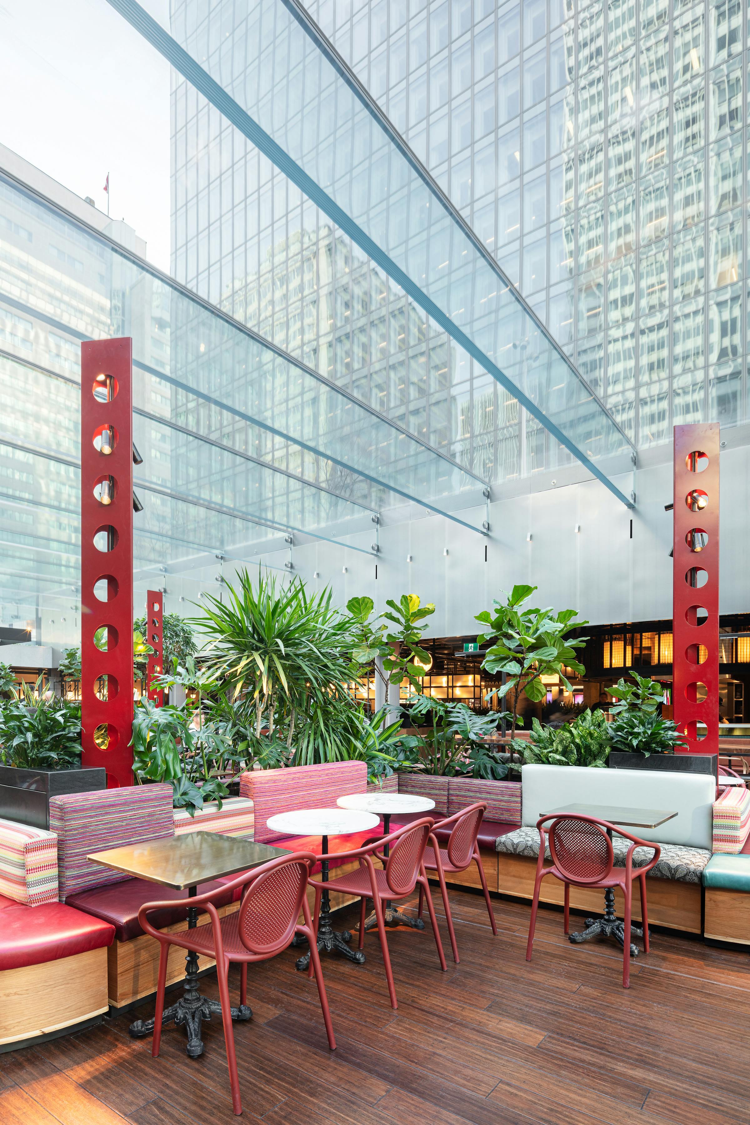 Photograph of an interior garden highlighting its architecture under a glass ceiling, with the majestic Place Ville-Marie in the background.