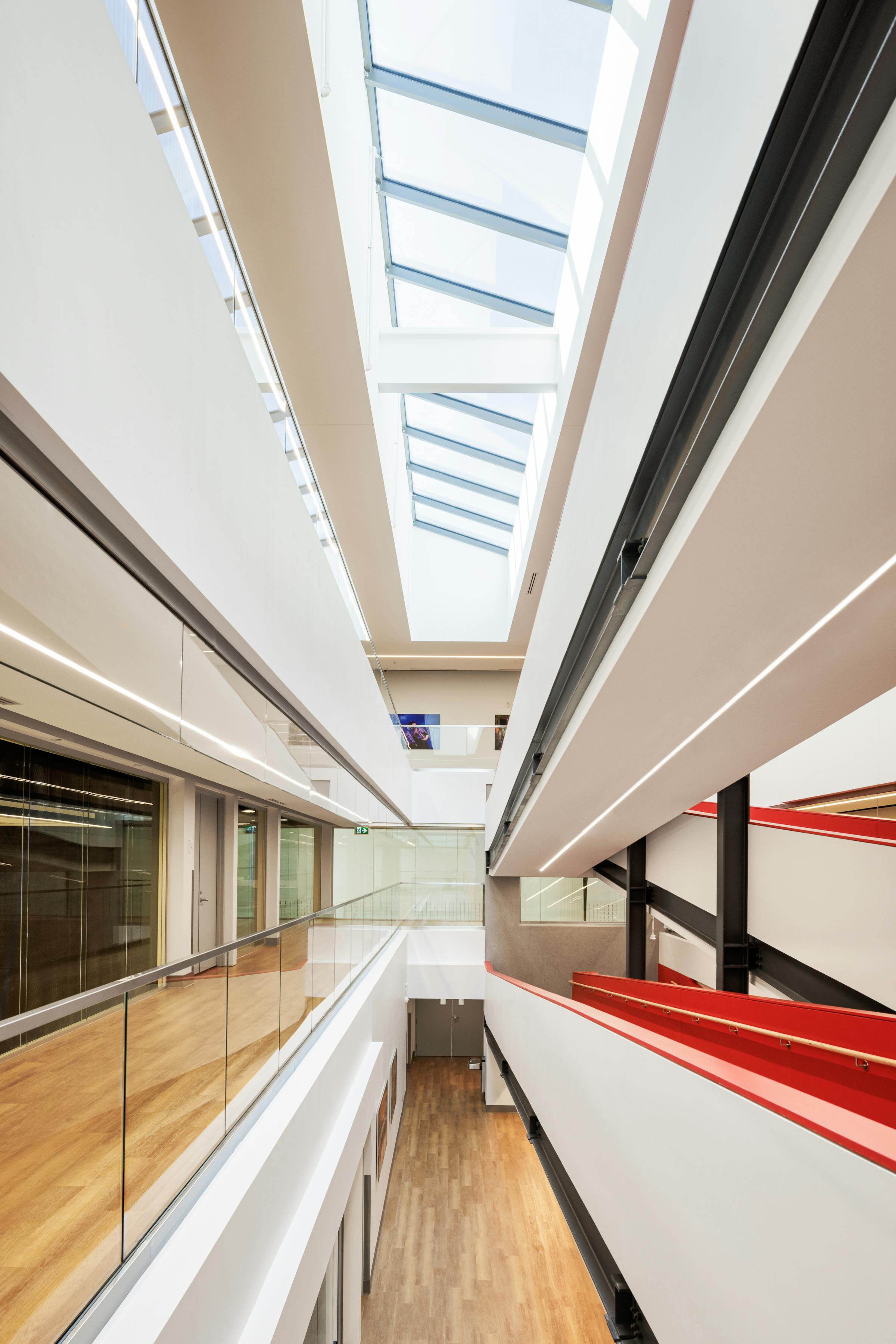 Photographie d'architecture d'un corridor. Vue très graphique avec beaucoup de lignes convergentes et le toit vitré de l'atrium.