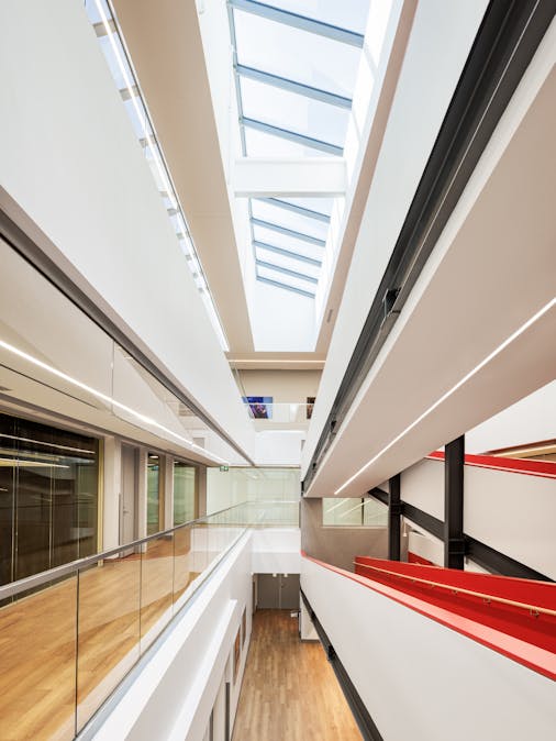 Photographie d'architecture d'un corridor. Vue très graphique avec beaucoup de lignes convergentes et le toit vitré de l'atrium.