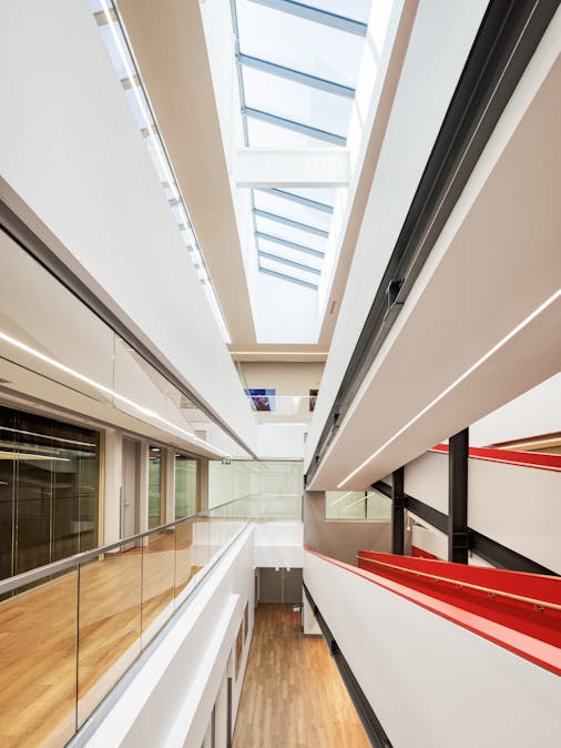Photographie d'architecture d'un corridor. Vue très graphique avec beaucoup de lignes convergentes et le toit vitré de l'atrium.