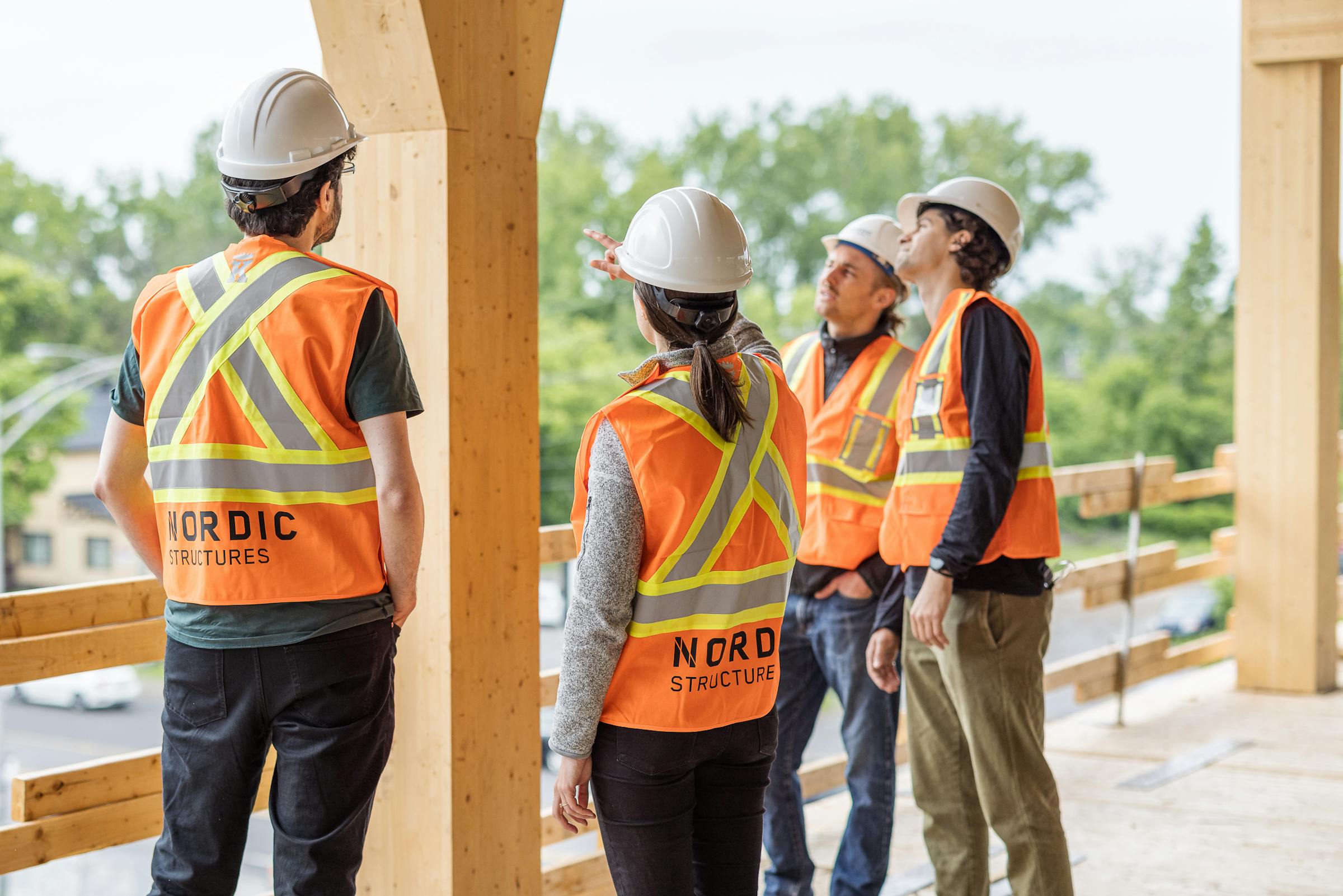 Photo of 4 Nordic structure workers examining a wooden structure on a construction site.