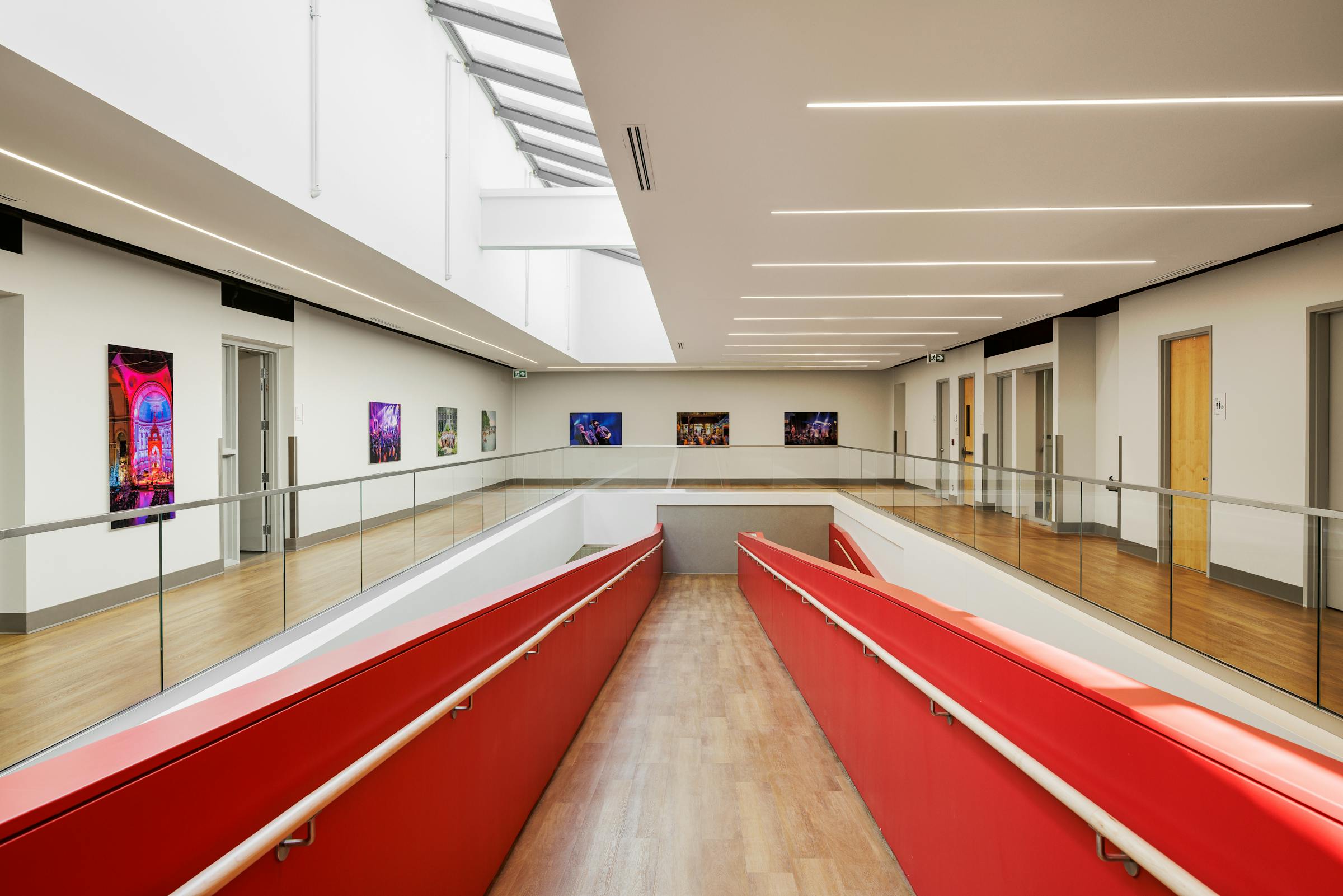 Photographie à un point de fuite du dernier étage d'un atrium avec des element architecturaux rouge qui contrastent avec les matériaux naturels.