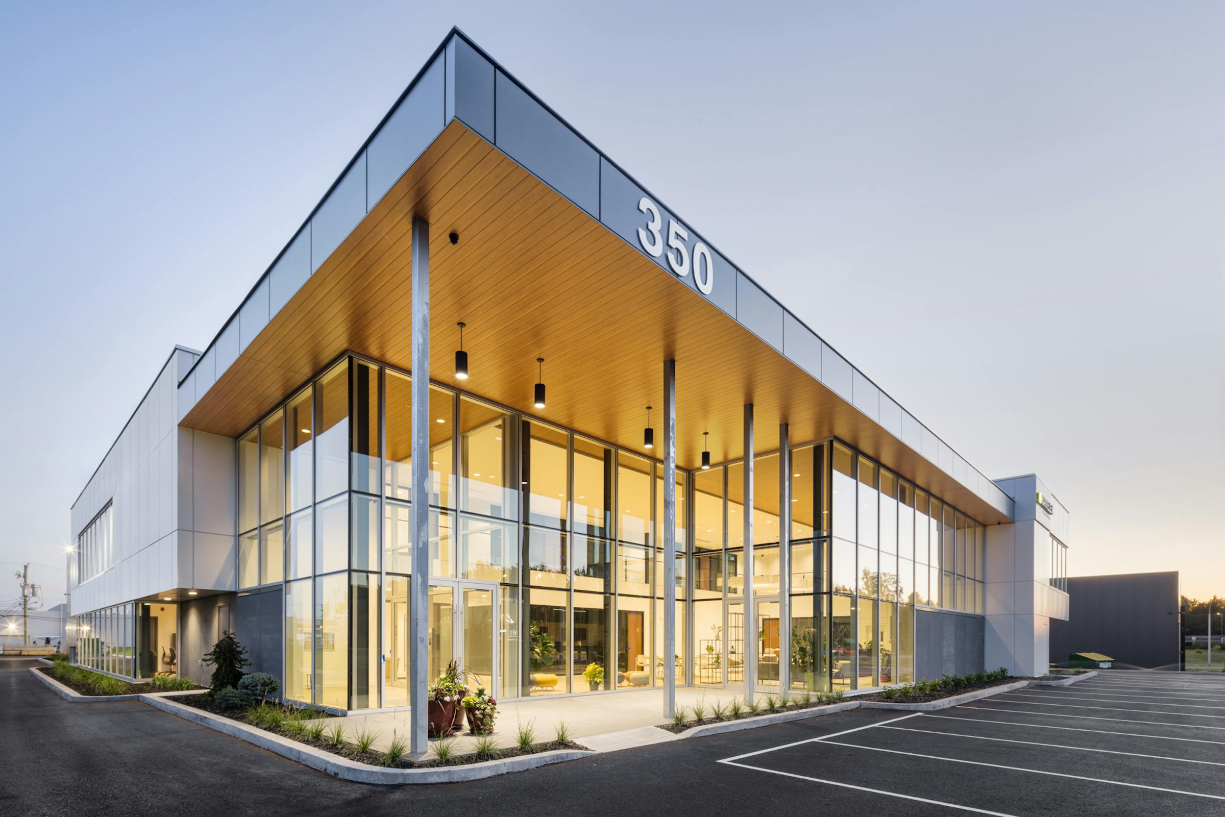 Architectural photography of a glazed commercial building at sunset. The interior light is very present.