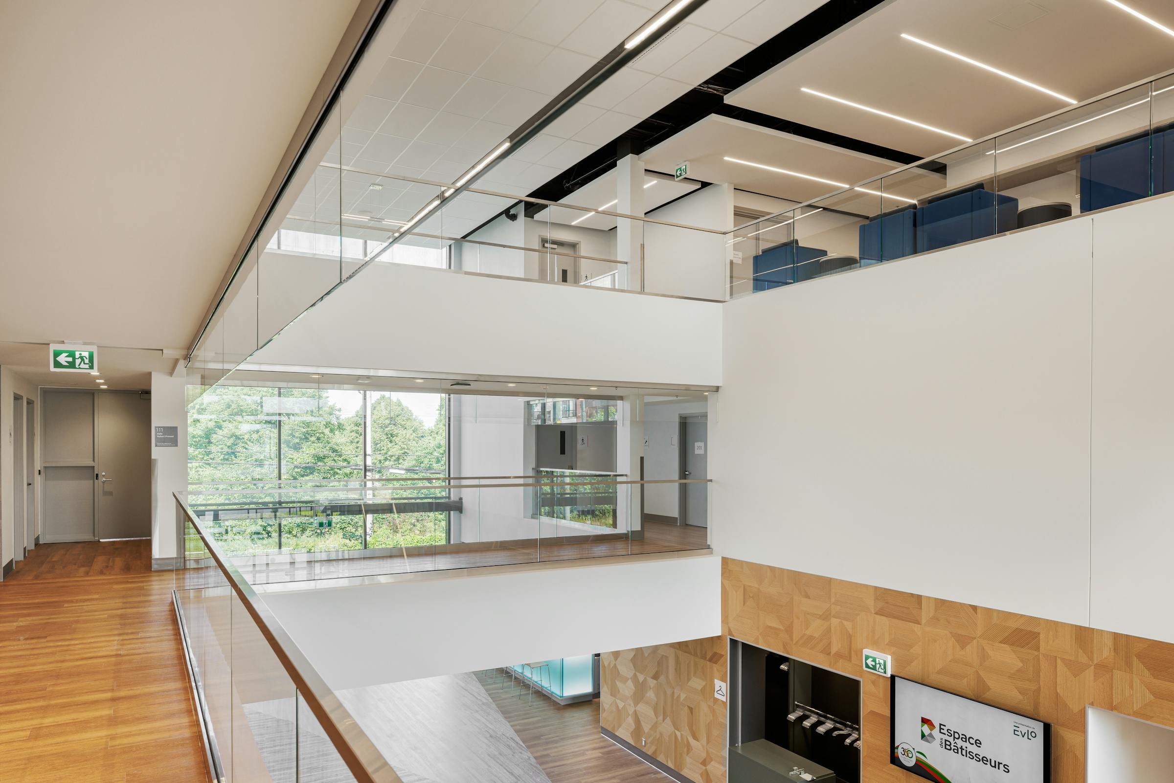 Photographie d'architecture intérieur d'un atrium avec 3 étages et des garde du corp vitrés.