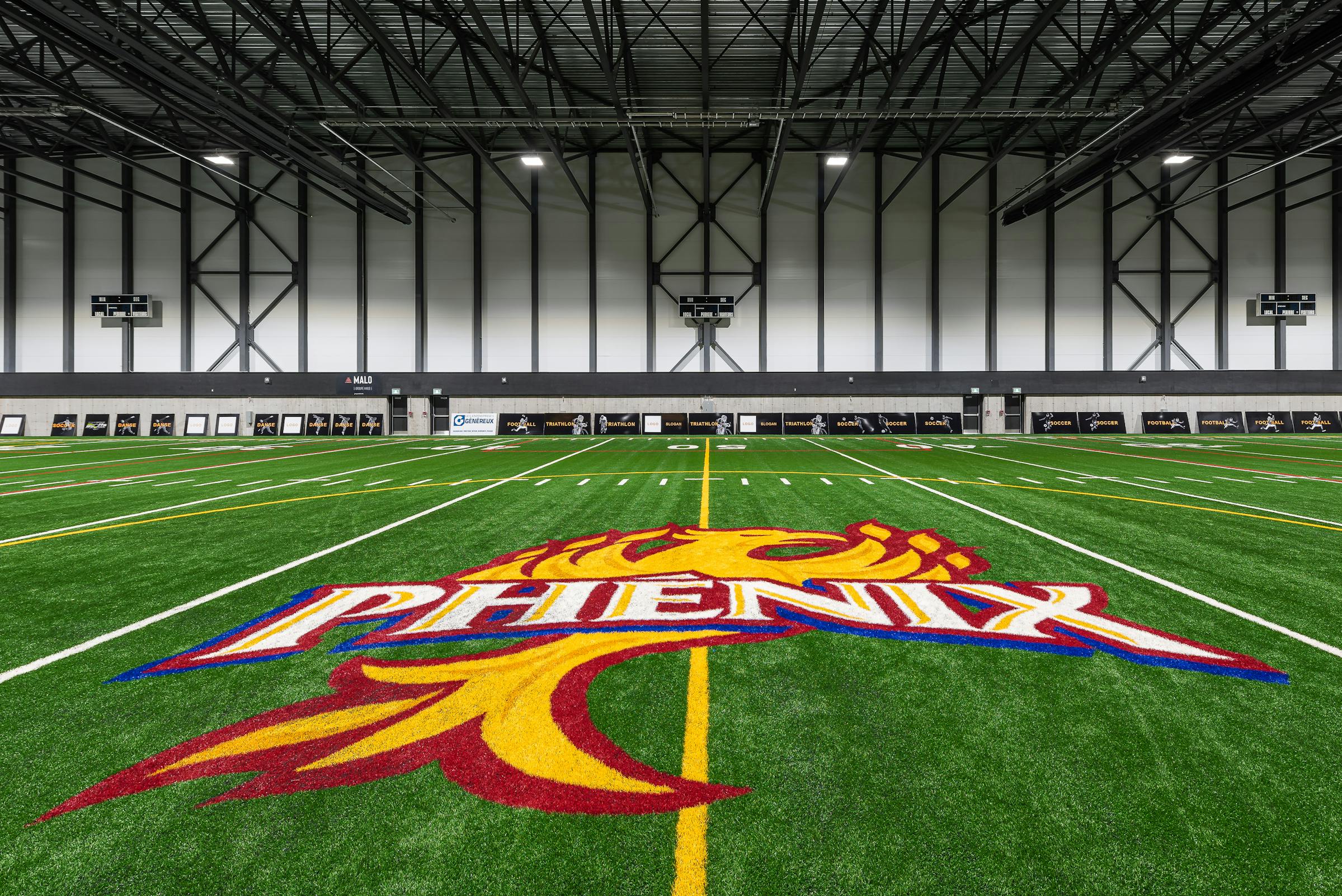 Photographie d'un terrain de soccer intérieur avec le logo de l'équipe au centre du terrain.