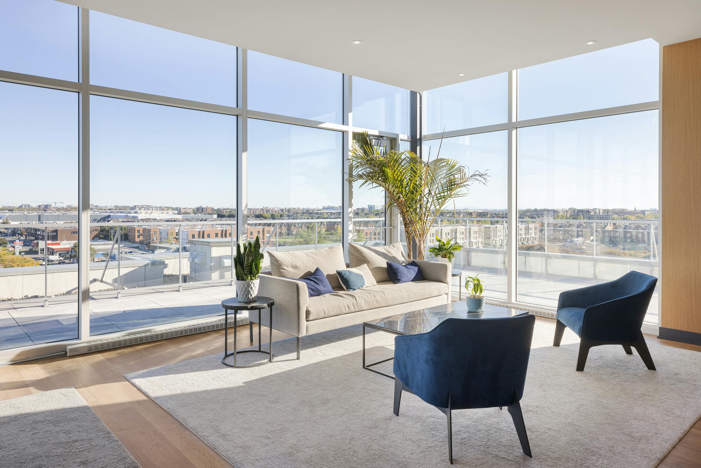 Design intérieur d'un salon panoramique avec de grandes baies vitrées et une vue sur la ville.