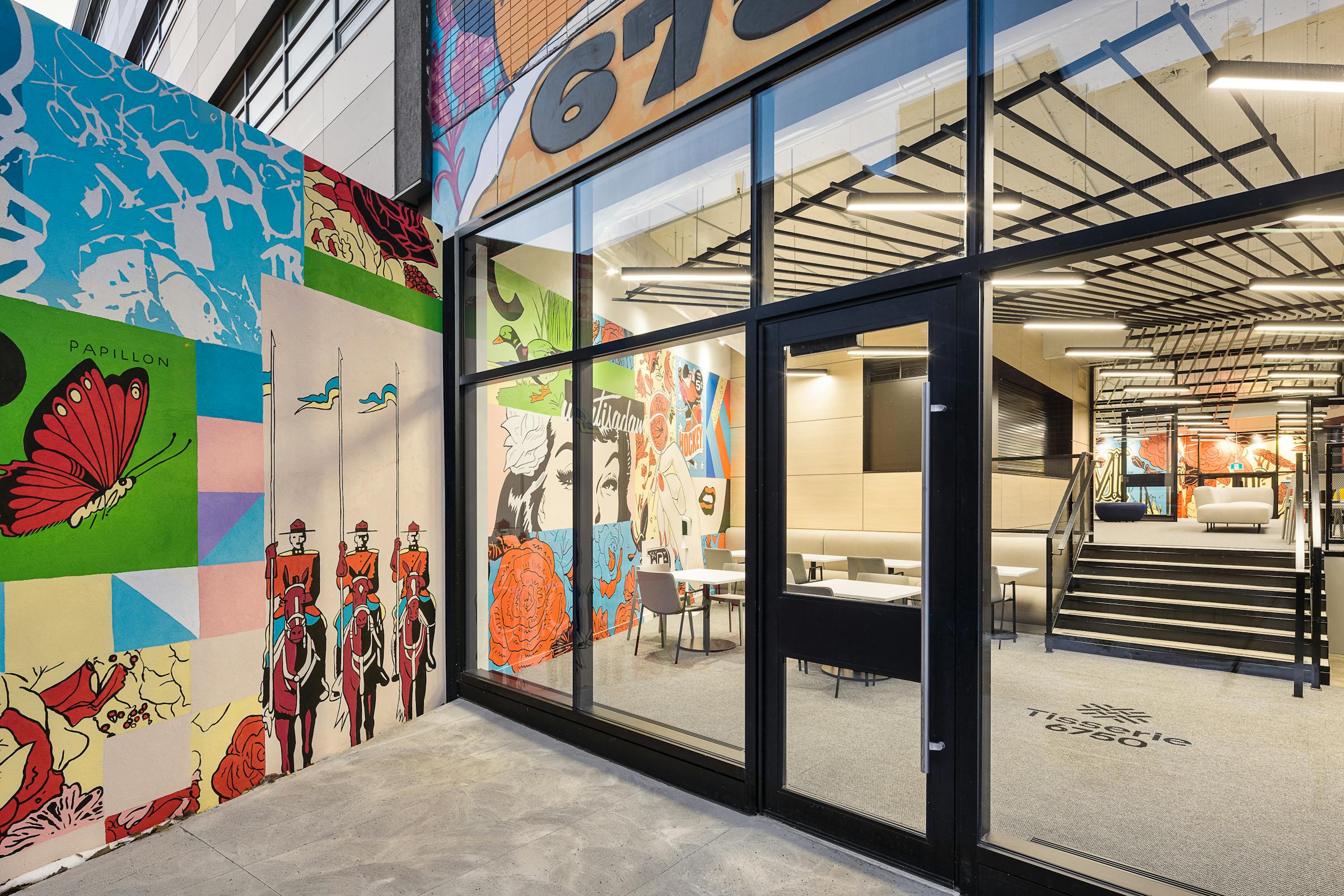 Photographie d'une vitrine laissant voir l'architecture et le design des aménagements intérieurs et la murale traversante.