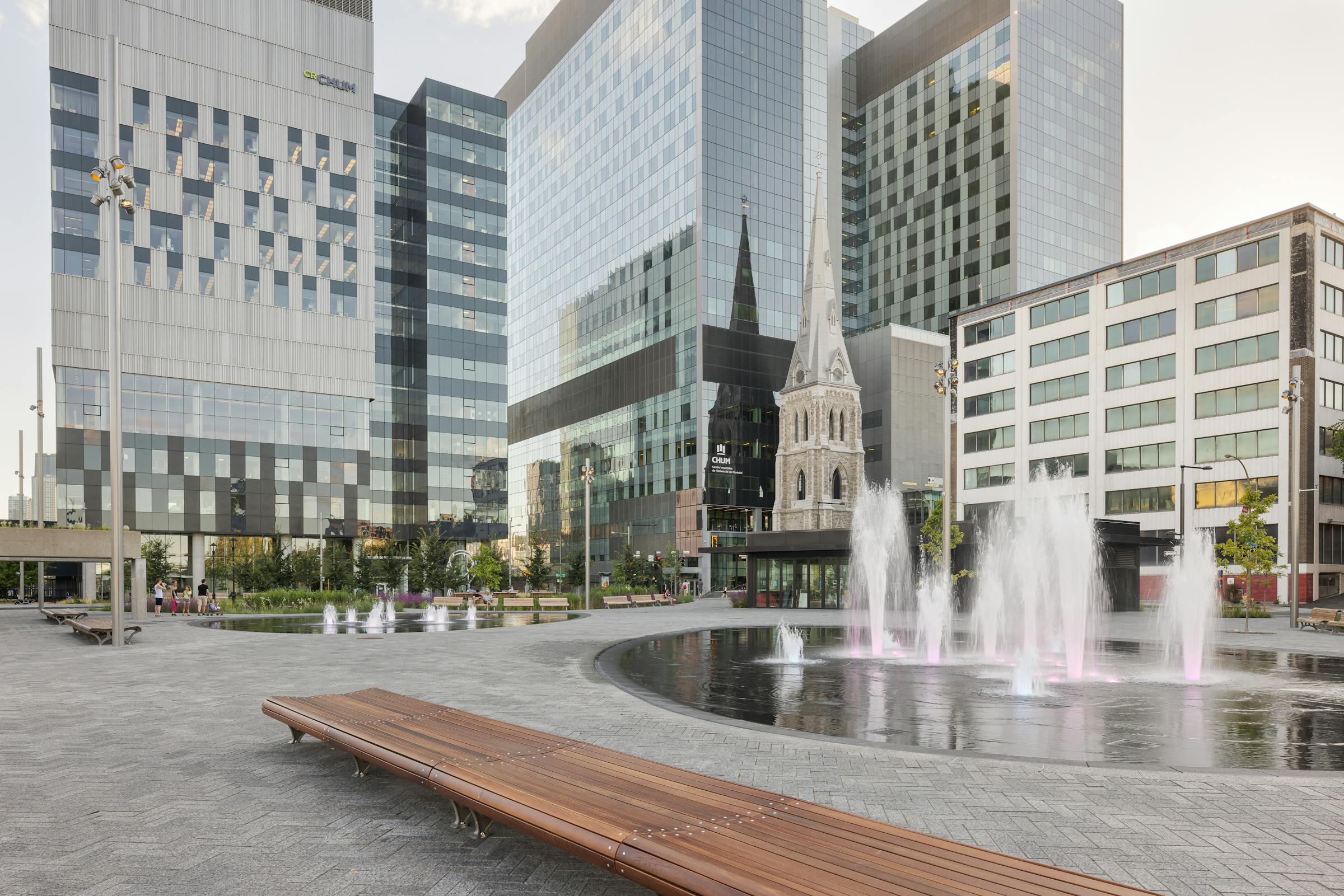 Architecture de paysage d'une place publique avec du mobilier urbain et des fontaines. Contraste fort entre l'architecture moderne et patrimoniale.