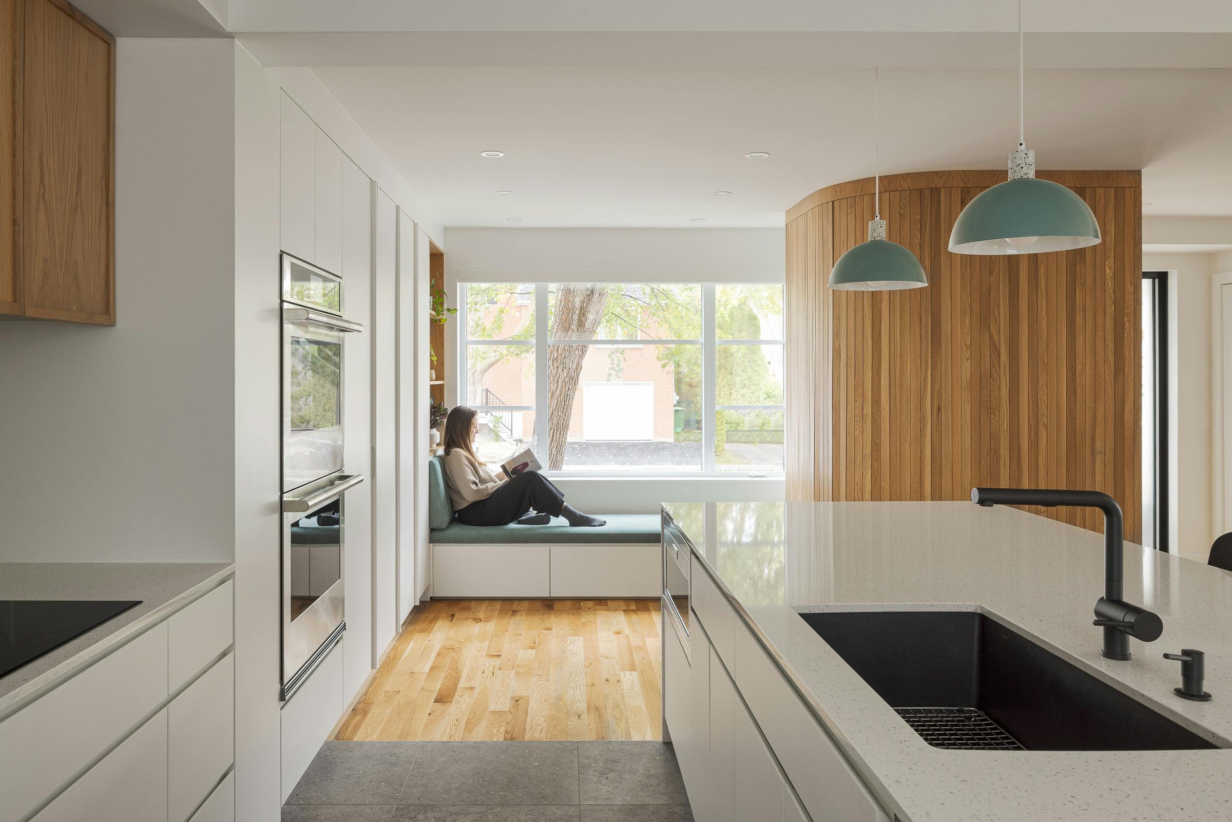 Perspective au travers de la cuisine ouverte sur le séjour d'une maison à l'architecture moderne et lumineuse.