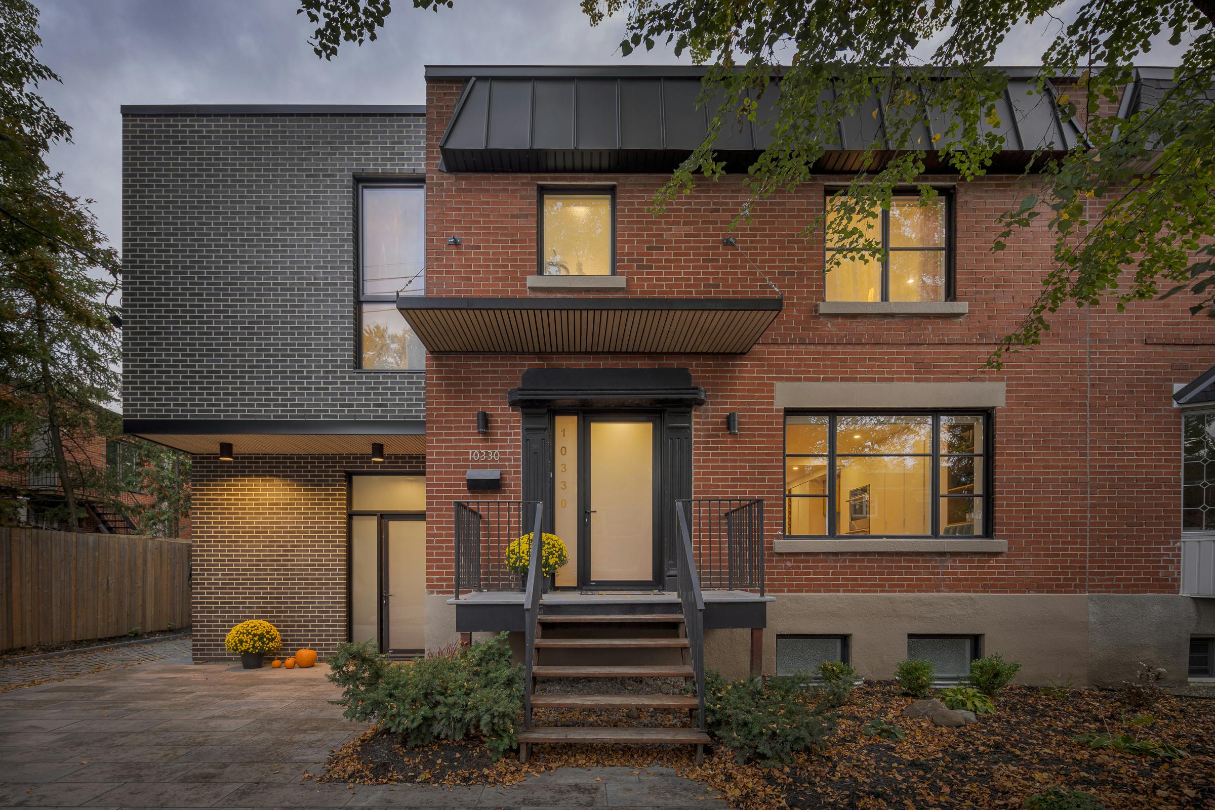 Façade d'une propriété résidentielle à Montréal au coucher du soleil. L'éclairage intérieur est bien visible au travers des fenêtres.