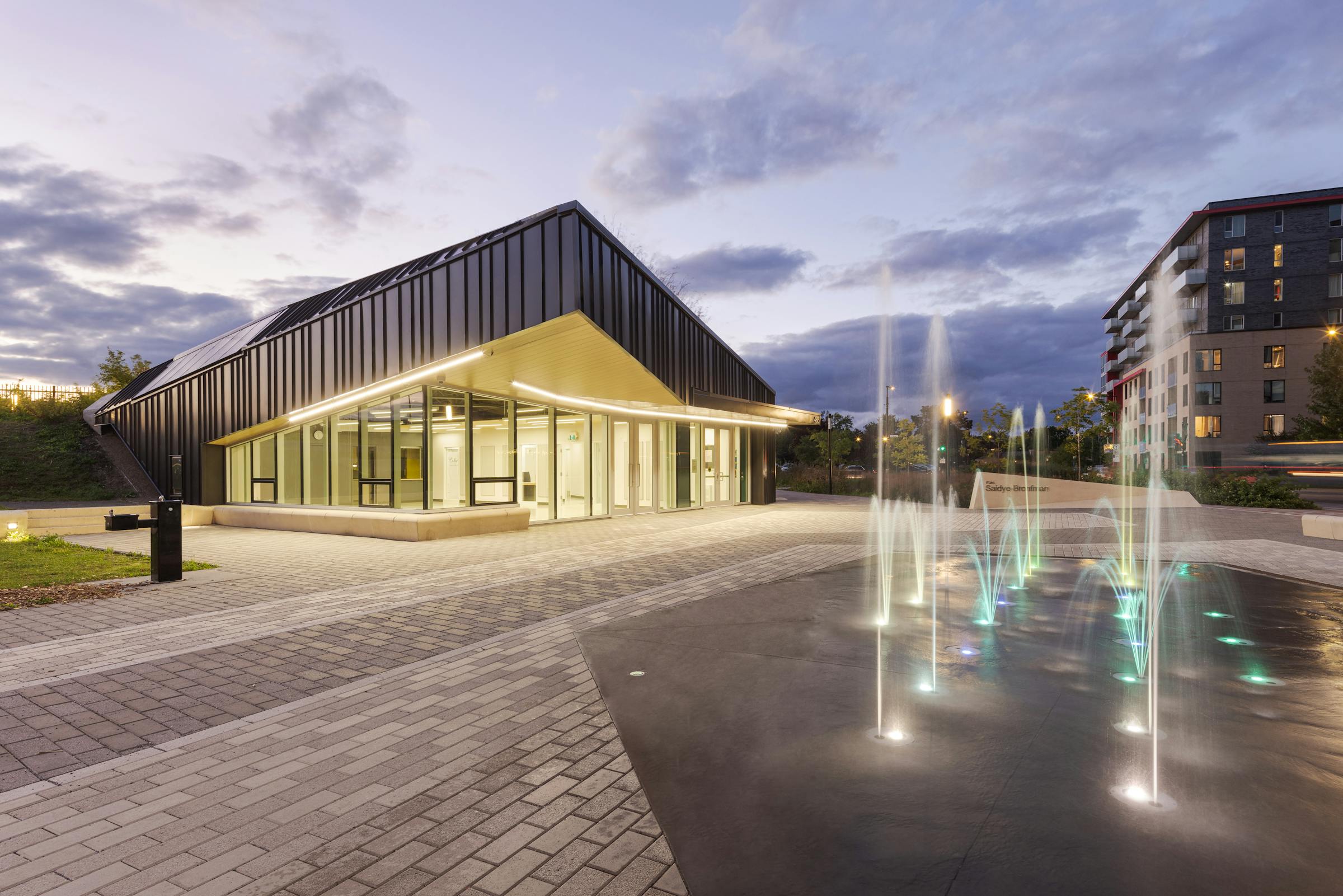 Blue hour architectural photography of a community centre, landscaping and public plaza.
