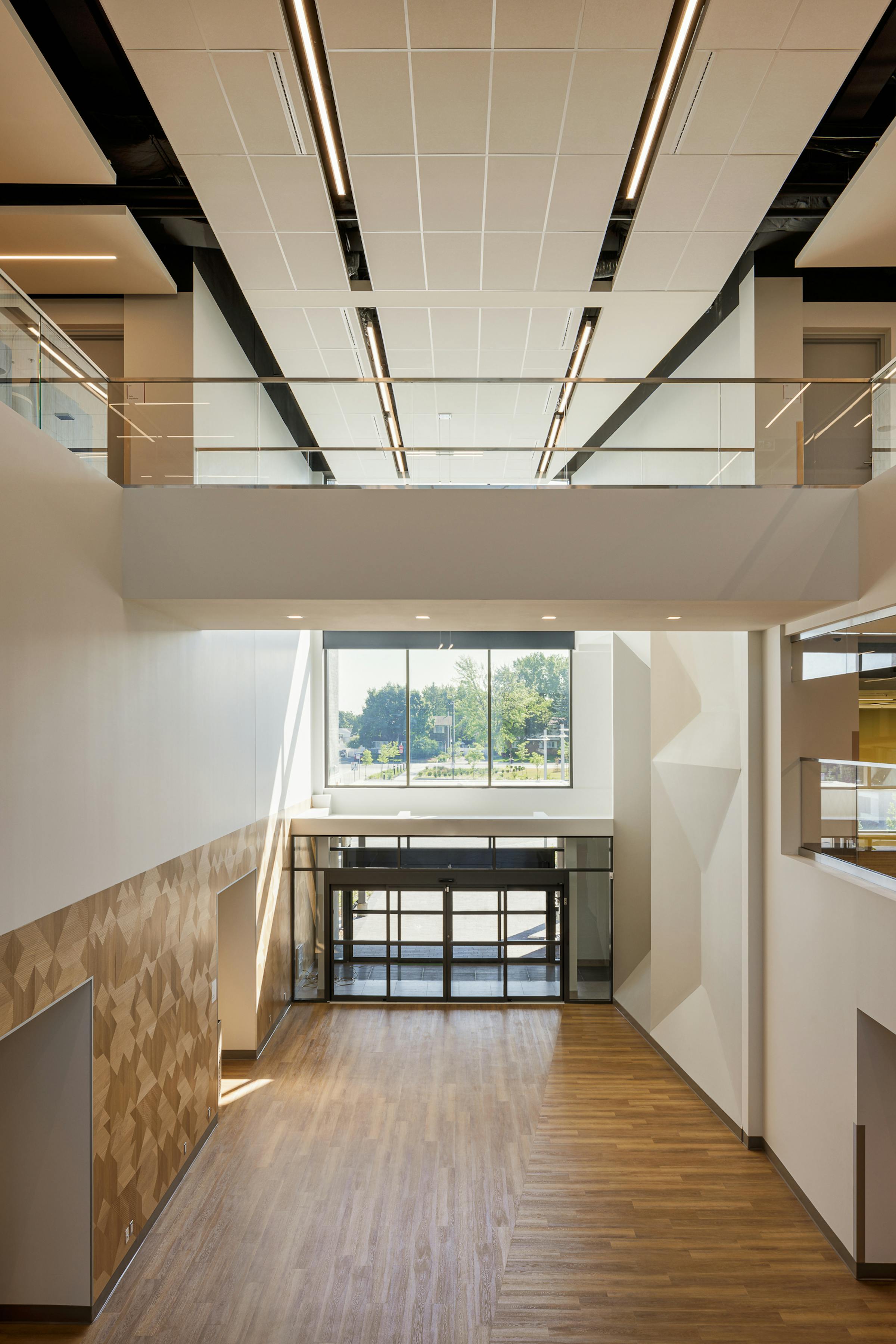 Architecture de l'entrée d'un bâtiment institutionnel à double hauteur avec une passerelle et un plancher de bois