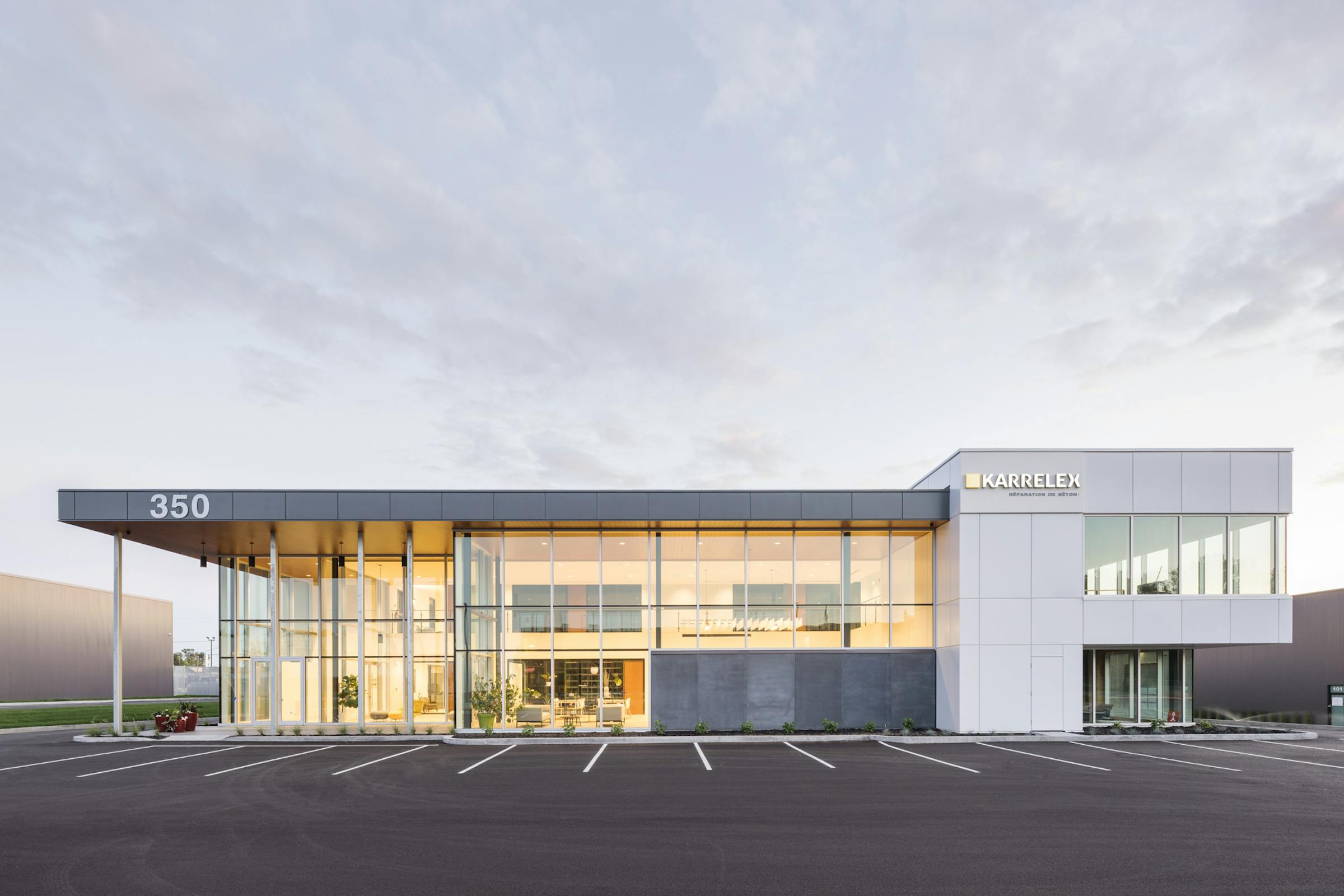 Architectural photography of a commercial building from the front at sunset with some clouds in the sky and a good balance between natural and artificial light.