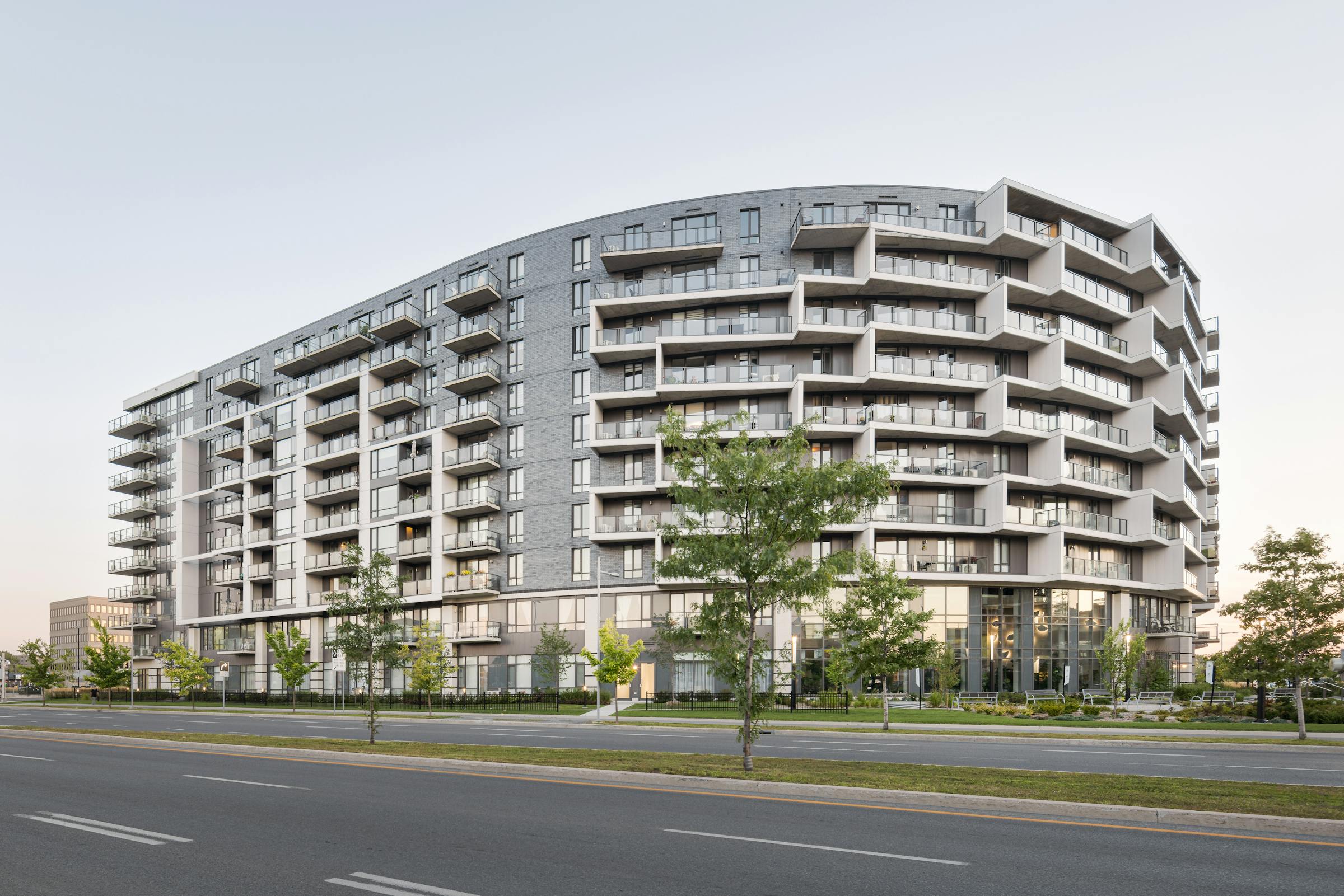 An architectural photograph of the rounded facade of a multi-residential building with soft light.