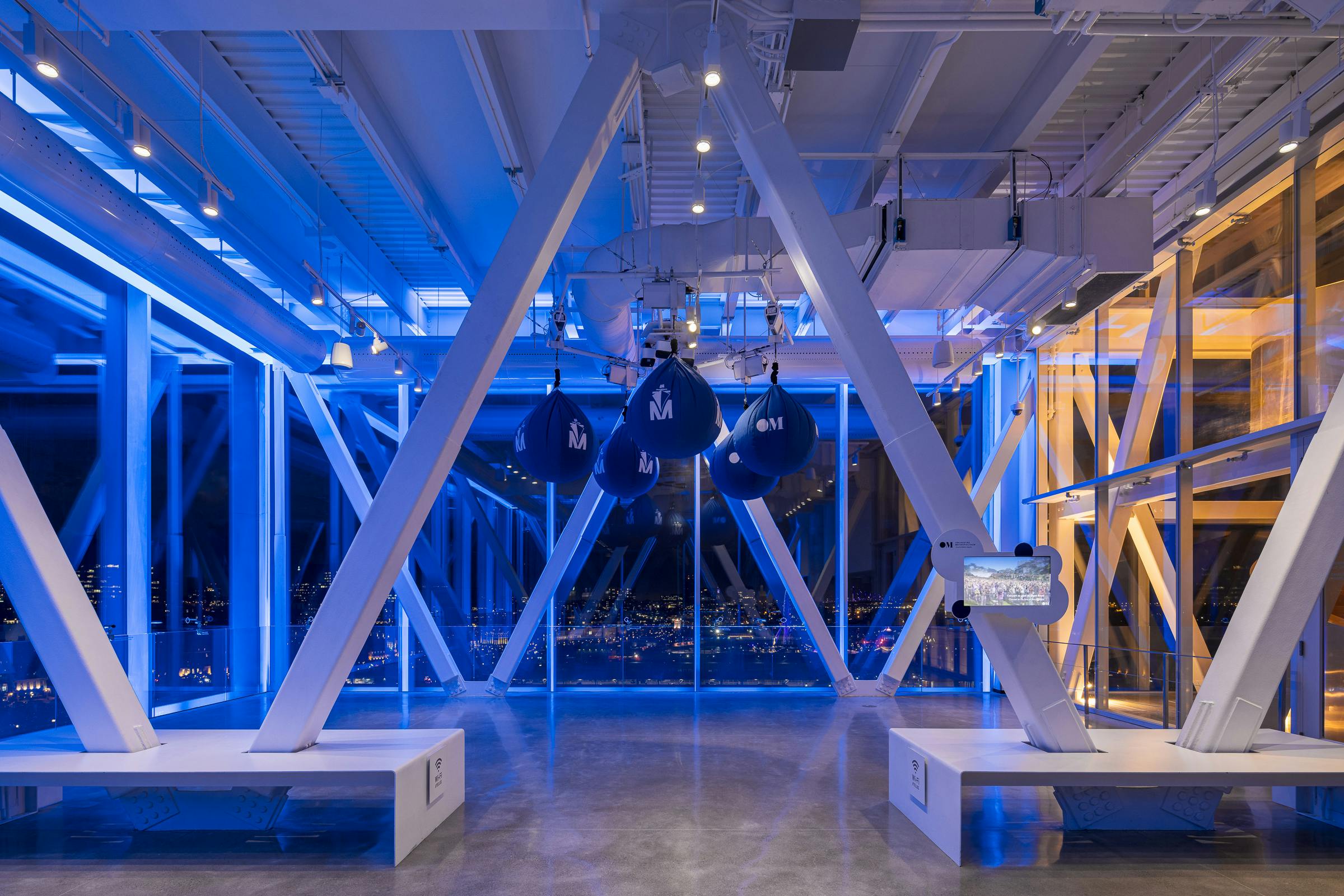 Night photograph of the interior of an observatory in the city of Montreal. Dominant blue artificial lighting.