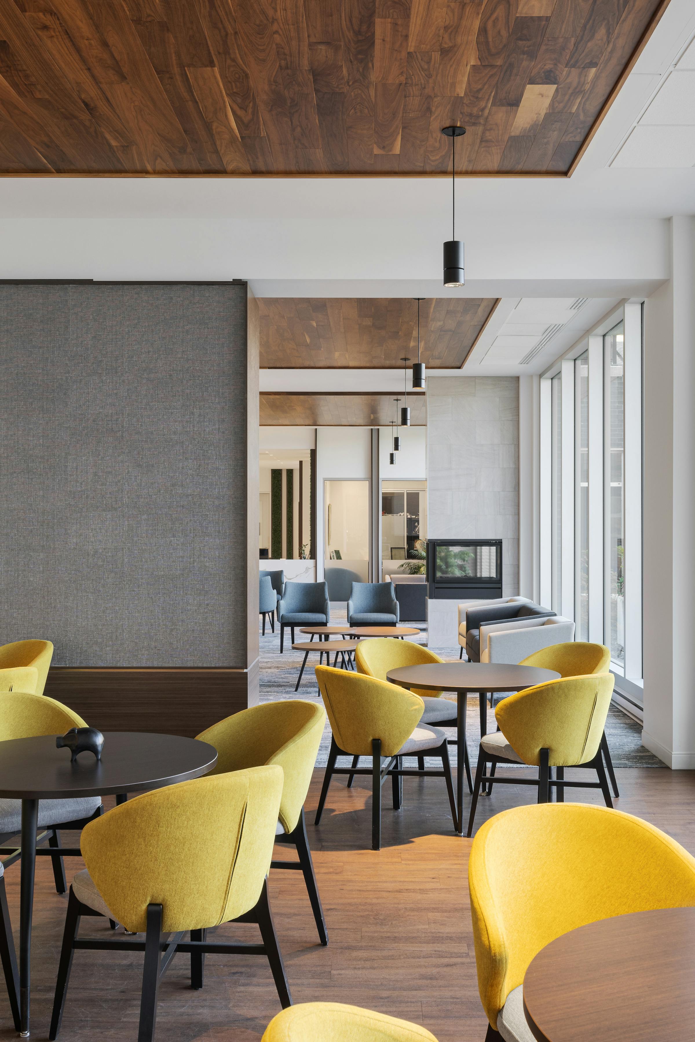 Perspective through several living rooms with colorful furniture, a bay window and hardwood floors.