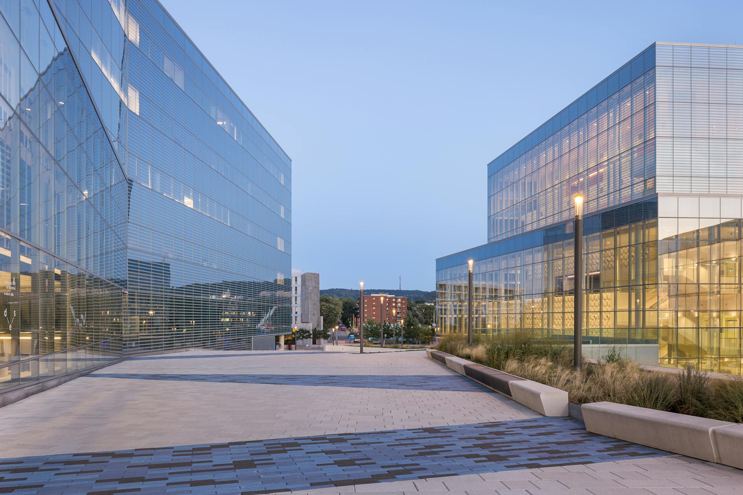 Architectural photograph of the MIL Campus in Outremont after sunset with public lighting and landscaping.
