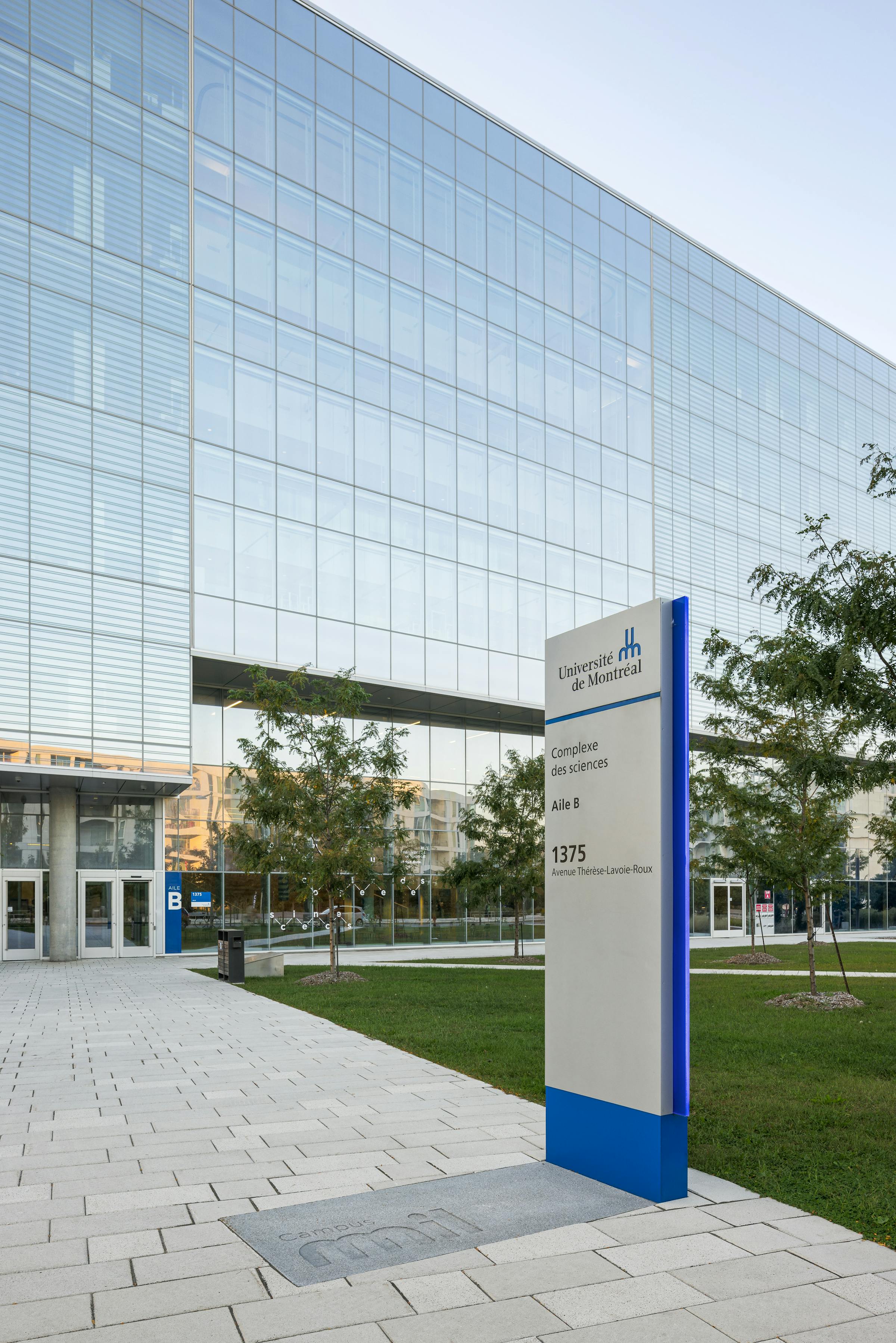 Photograph of an institutional building with the University of Montreal sign in the foreground.