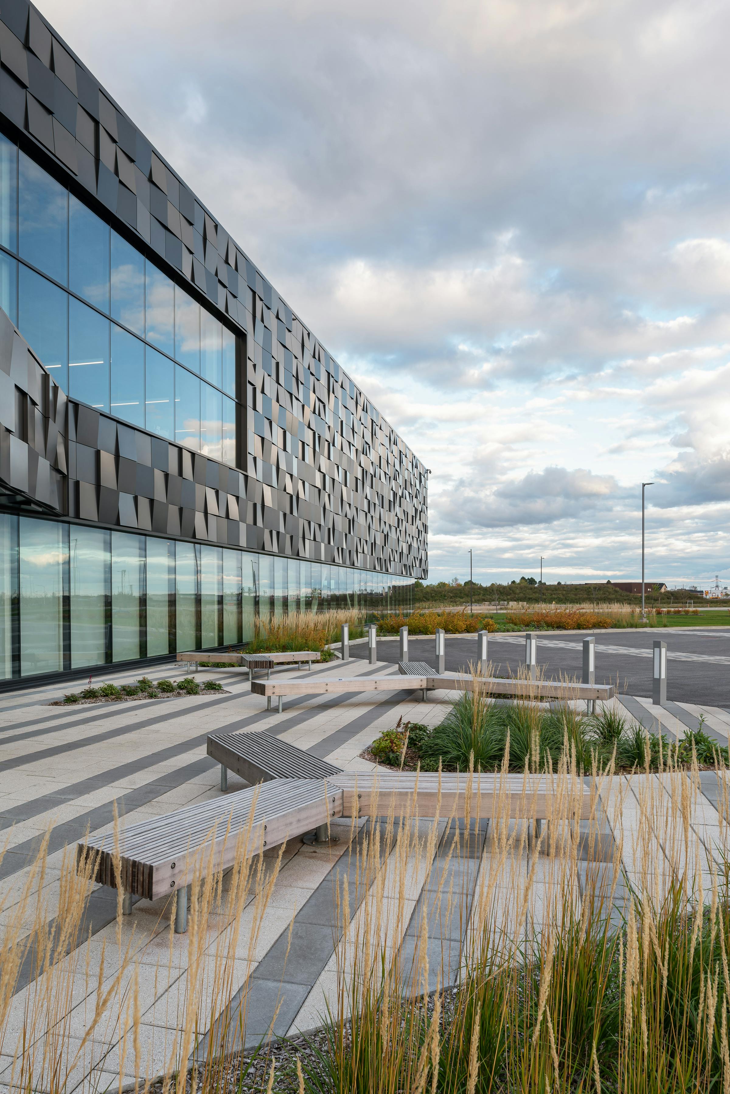 Landscape architecture photography of a commercial building. Plantations, paving stones and street furniture in the foreground.