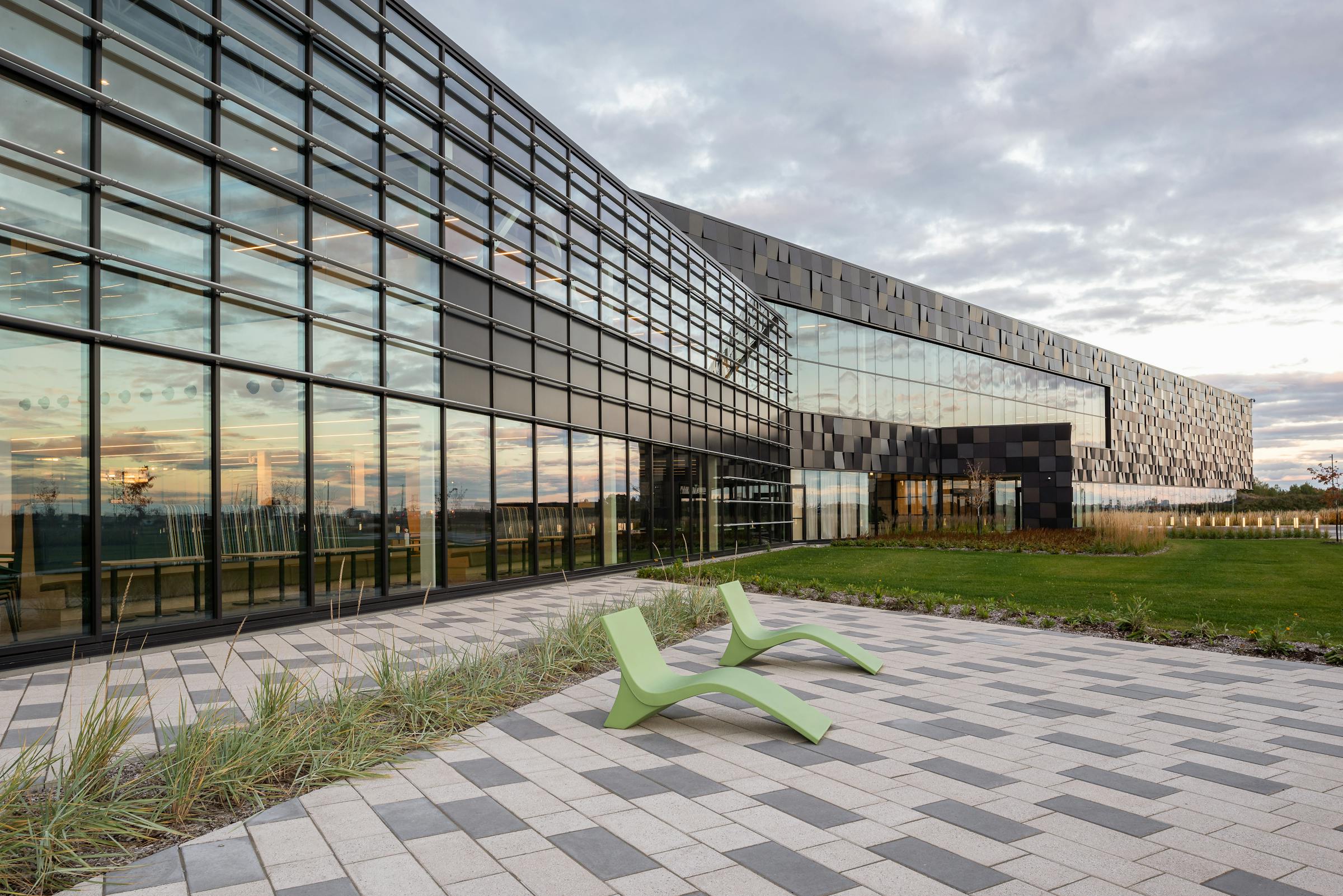 Exterior architectural photograph of a distribution center in Quebec. The windows reflect the sunset