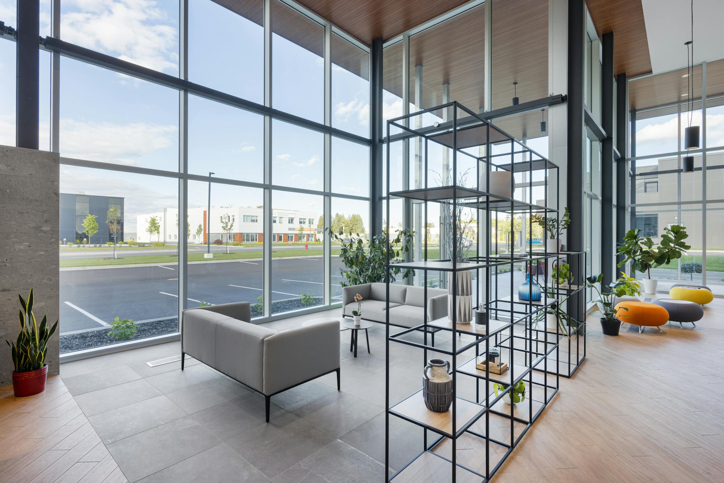 Interior design photography of a commercial space in Blainville. Shelves, living room and large bay window with view on the outside.