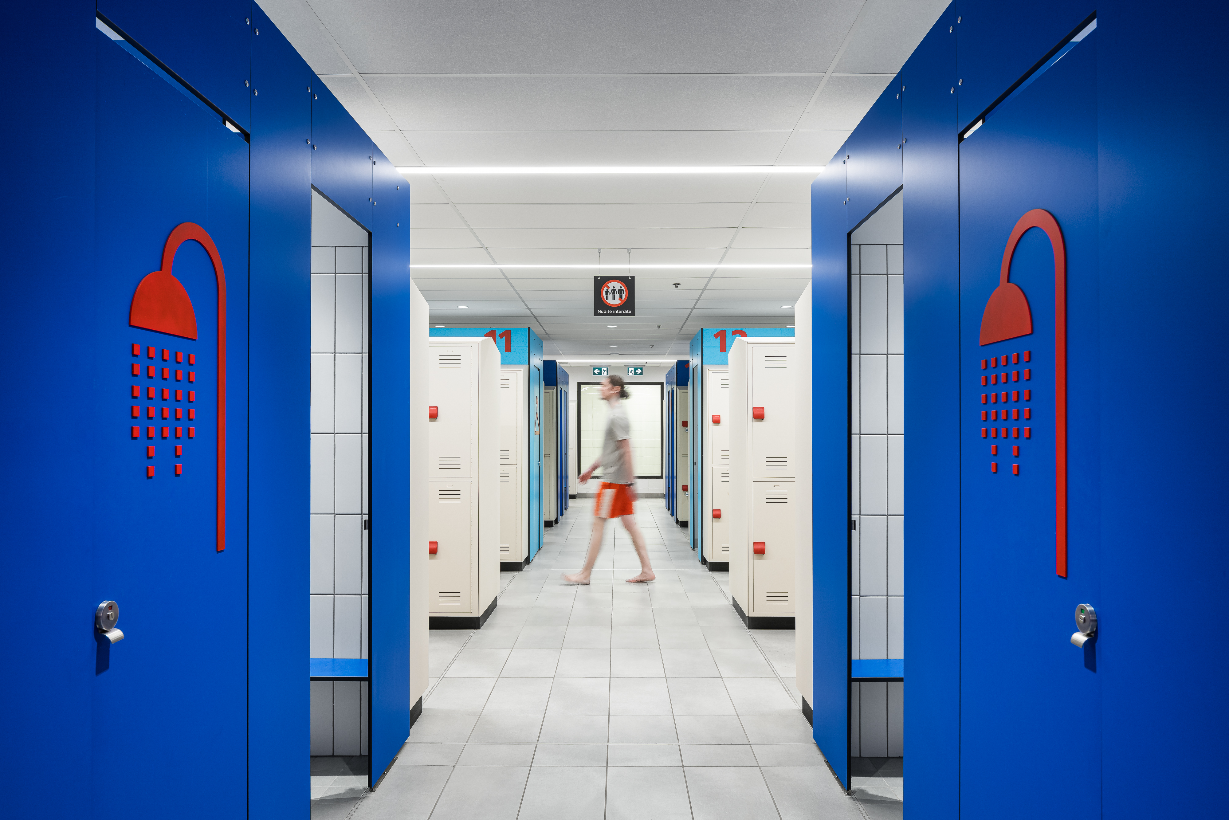 Interior design photograph, row of individual blue cubicles with shower pictograms.