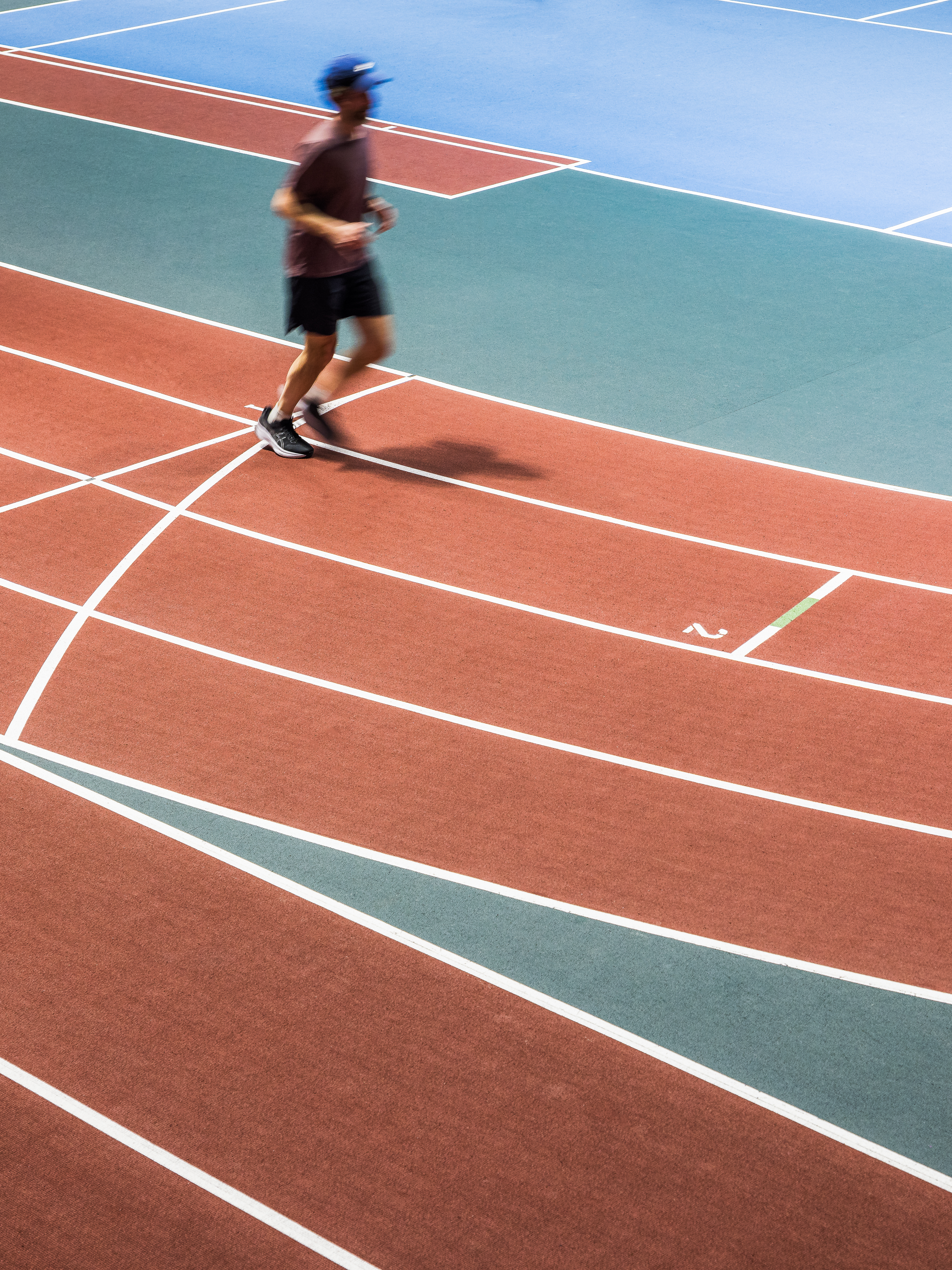 Architectural photograph of an athlete running on the indoor track of the Claude-Robillard Sports Complex's multi-sports hall.
